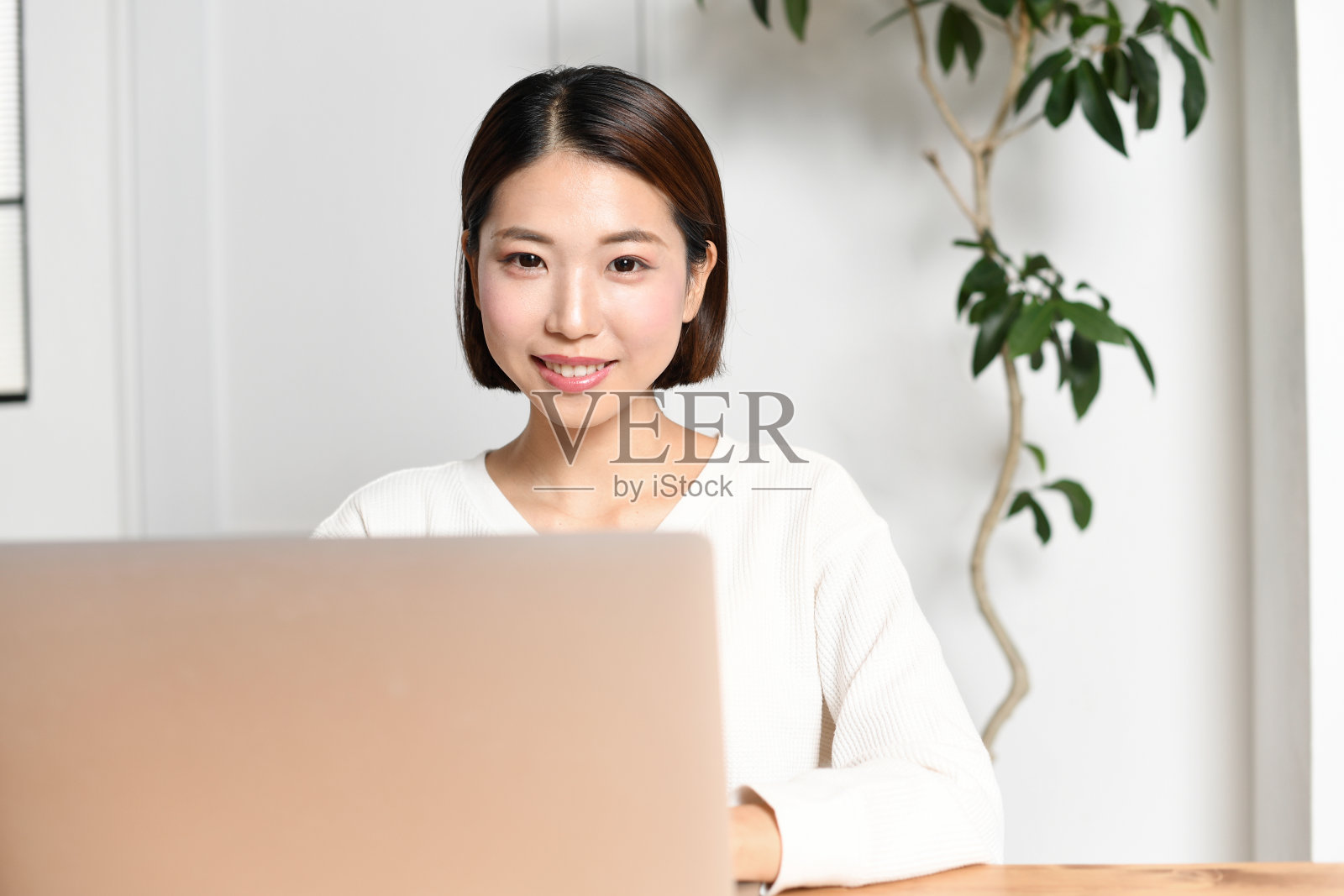 一位穿着休闲装的年轻亚洲女性微笑着在笔记本电脑上工作照片摄影图片