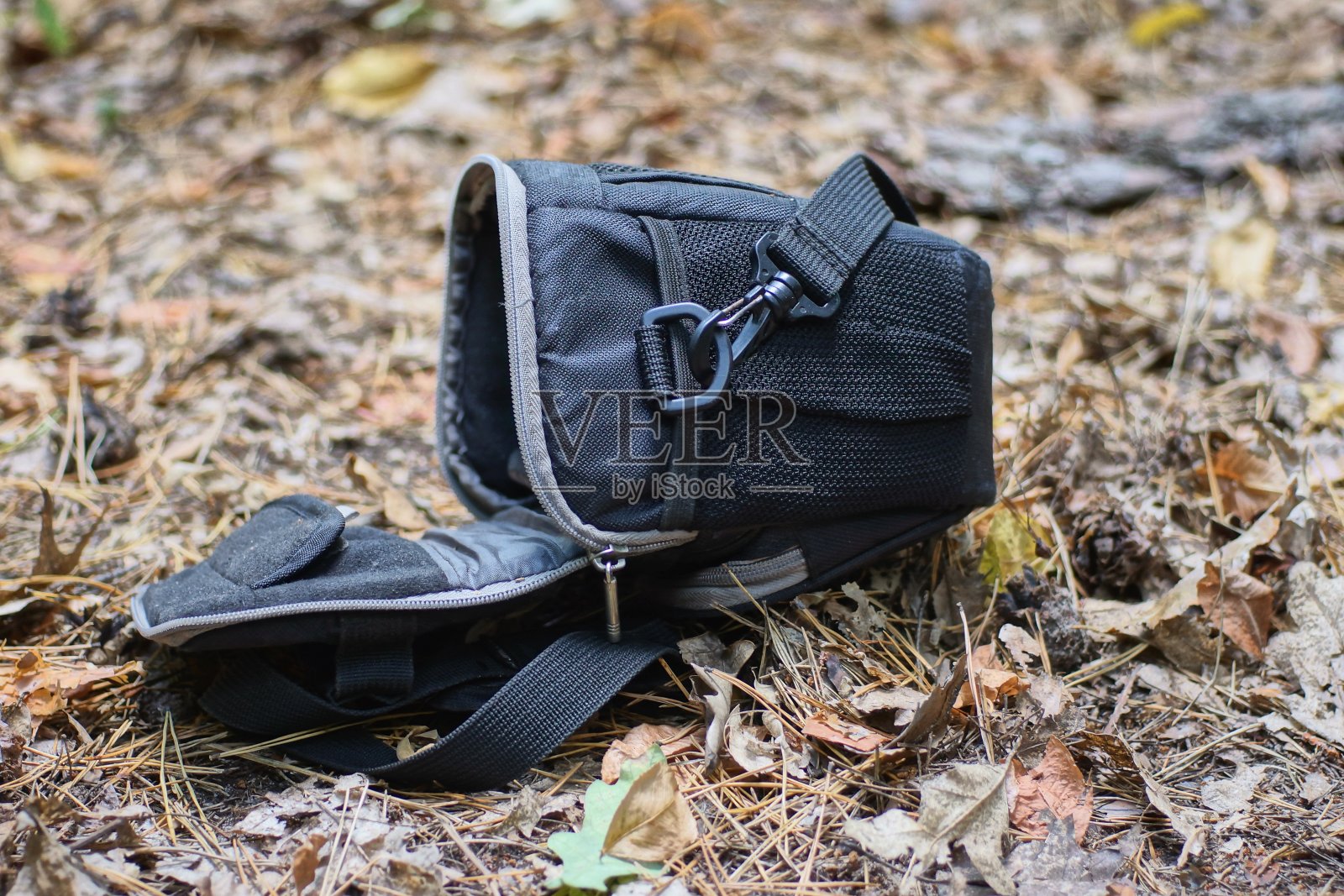 灰色的干草地上躺着一个开着的黑色小布袋照片摄影图片