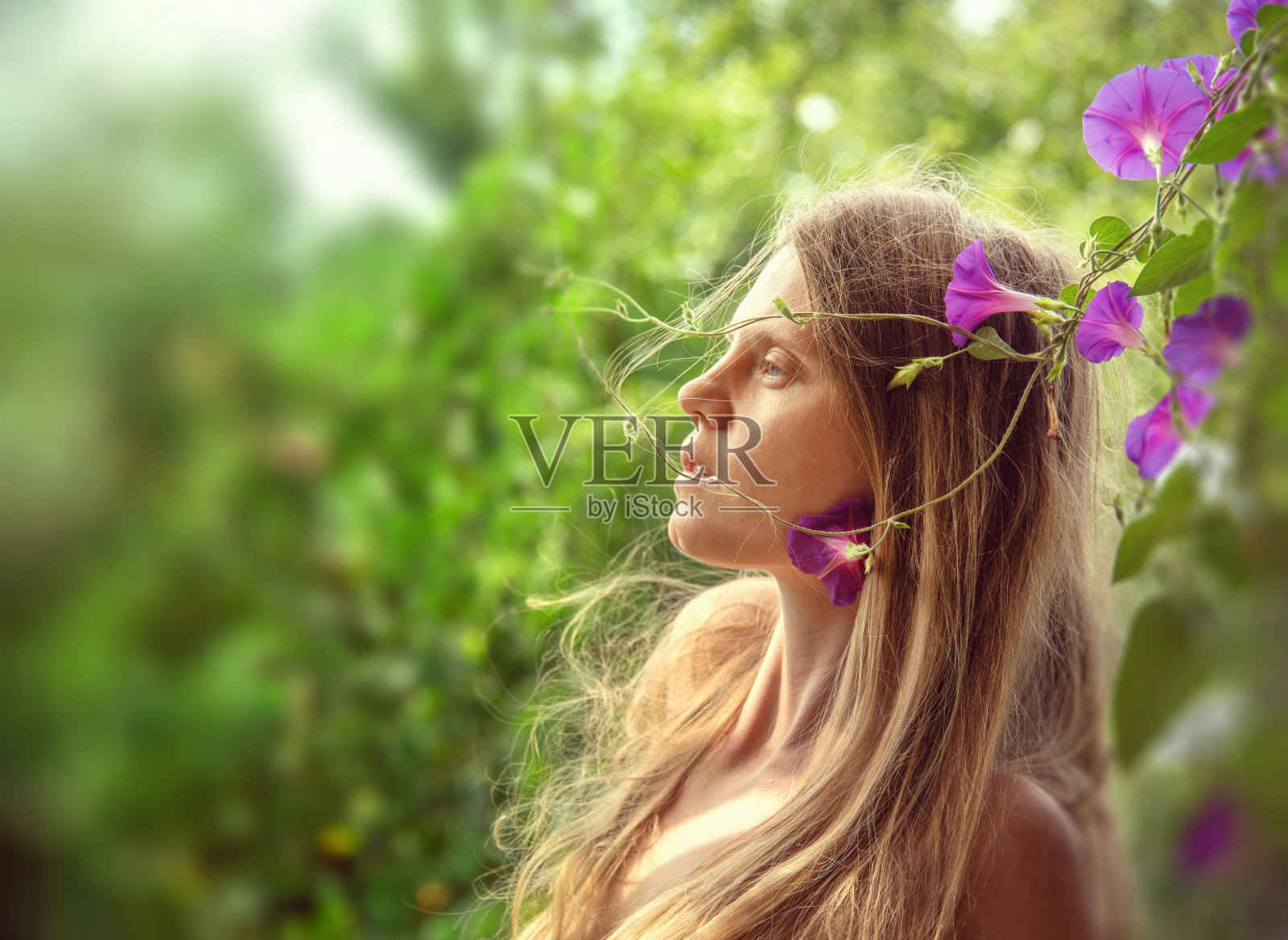 年轻女子的肖像在郁郁葱葱的树叶与鲜花在大自然照片摄影图片