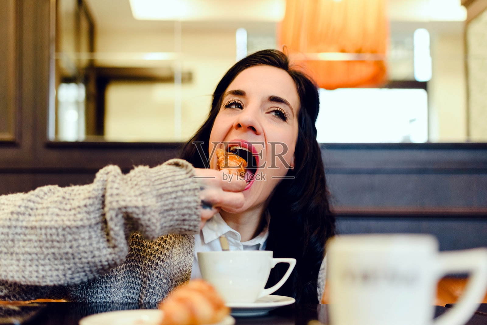 中年妇女,真实的人,在咖啡店吃牛角包配咖啡。照片摄影图片