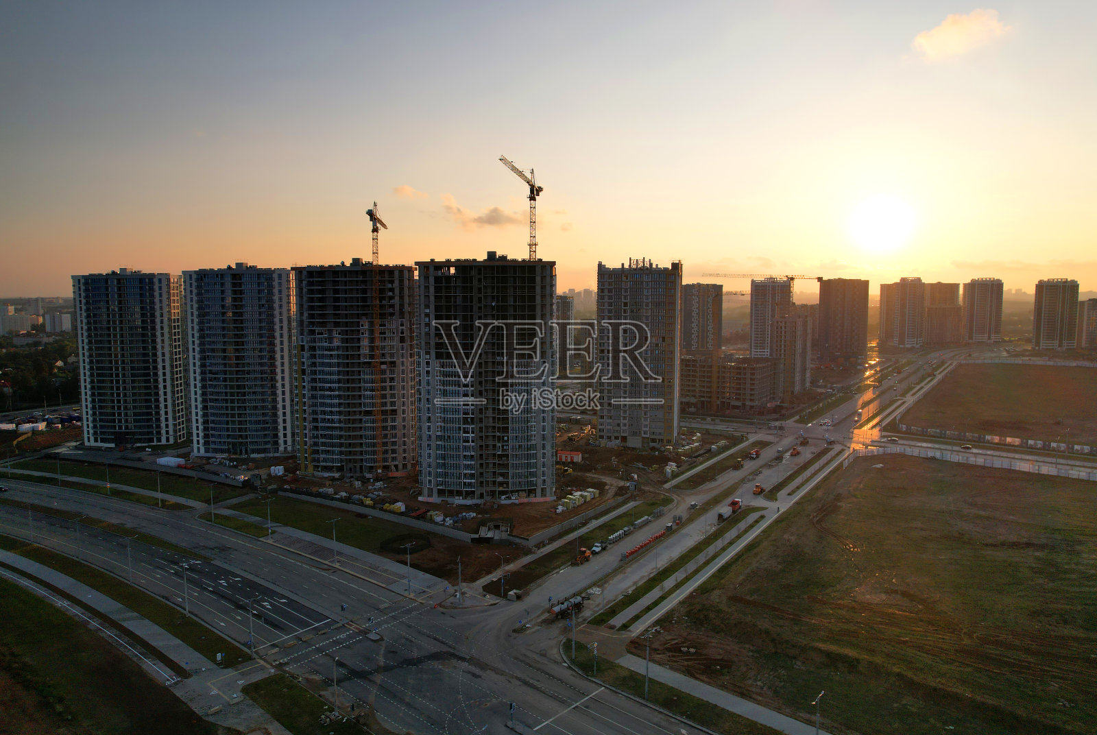 夕阳下的建筑工地塔吊鸟瞰图。建筑施工照片摄影图片