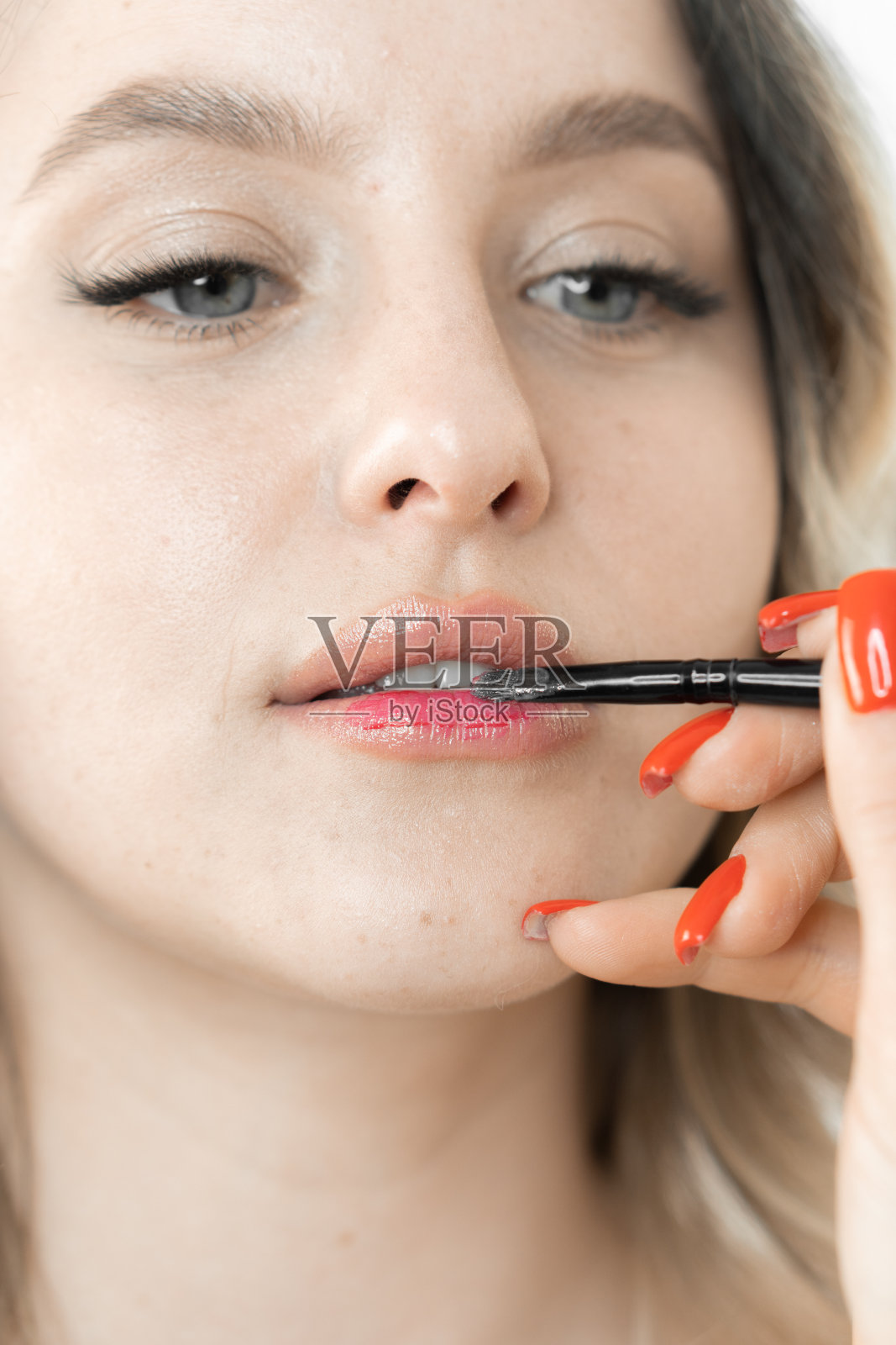 在美容院,一位年轻女子正在欣赏专业化妆师给她画的优美唇妆。面部体现自然之美,时尚细节突出。在美容院画唇妆照片摄影图片