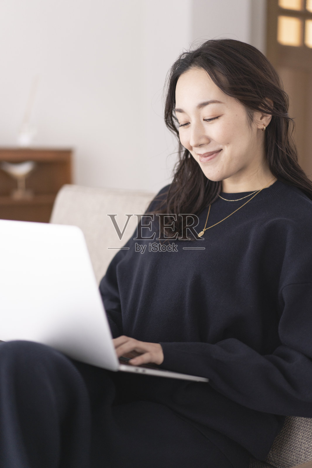 一位亚洲妇女正在用笔记本电脑工作。照片摄影图片