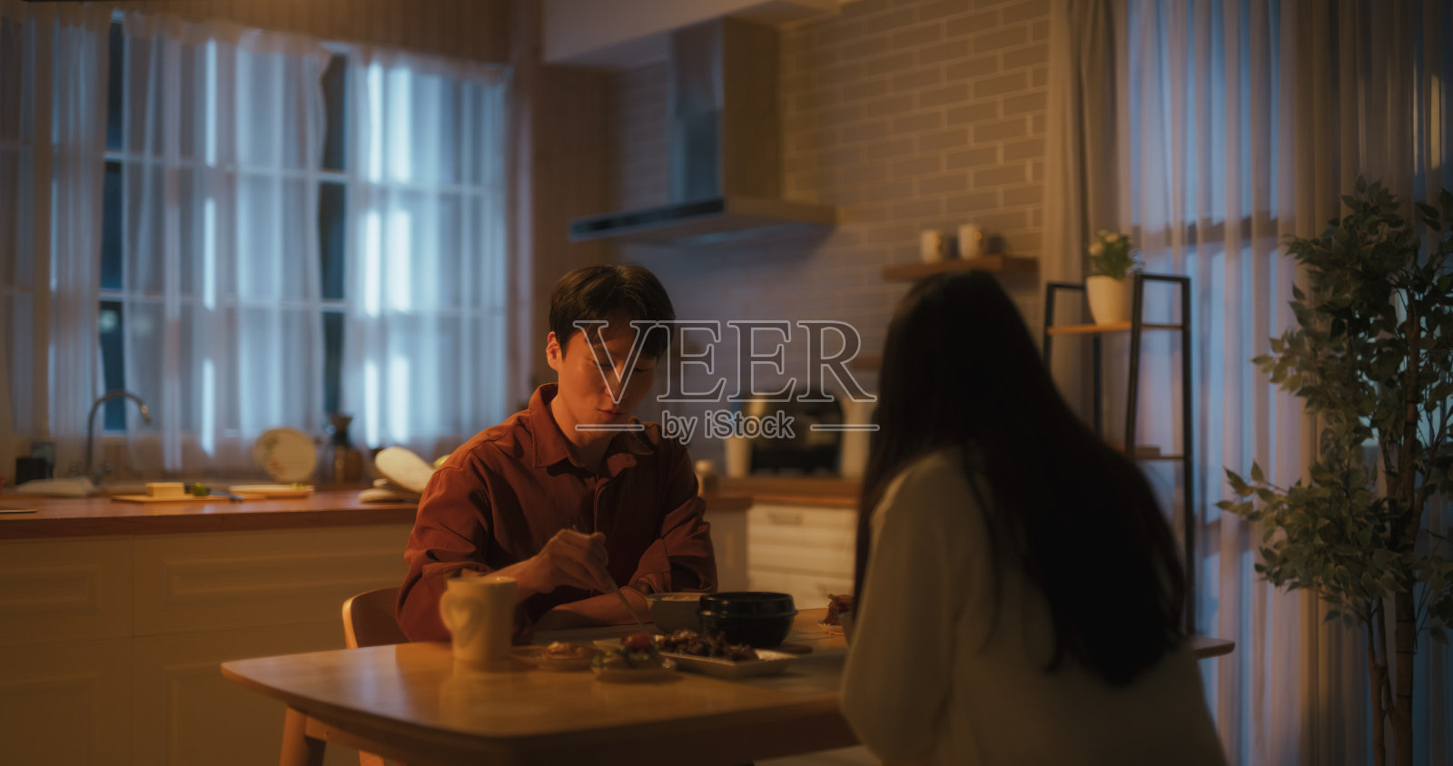 韩国年轻夫妇在家做饭,一起在厨房吃饭。有爱的男人和女人准备了传统的韩国菜,猪肉,辣蔬菜汤和米饭照片摄影图片