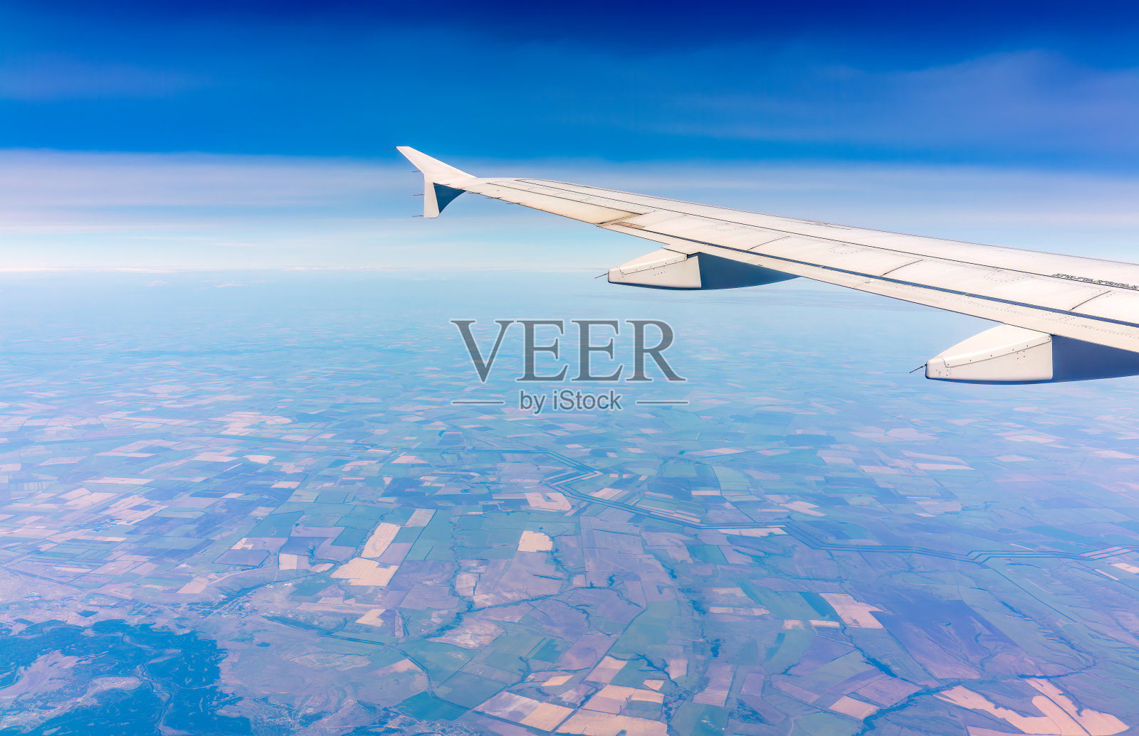 从飞机窗口俯瞰绿色地面。从飞机窗口看到日出时美丽的云照片摄影图片