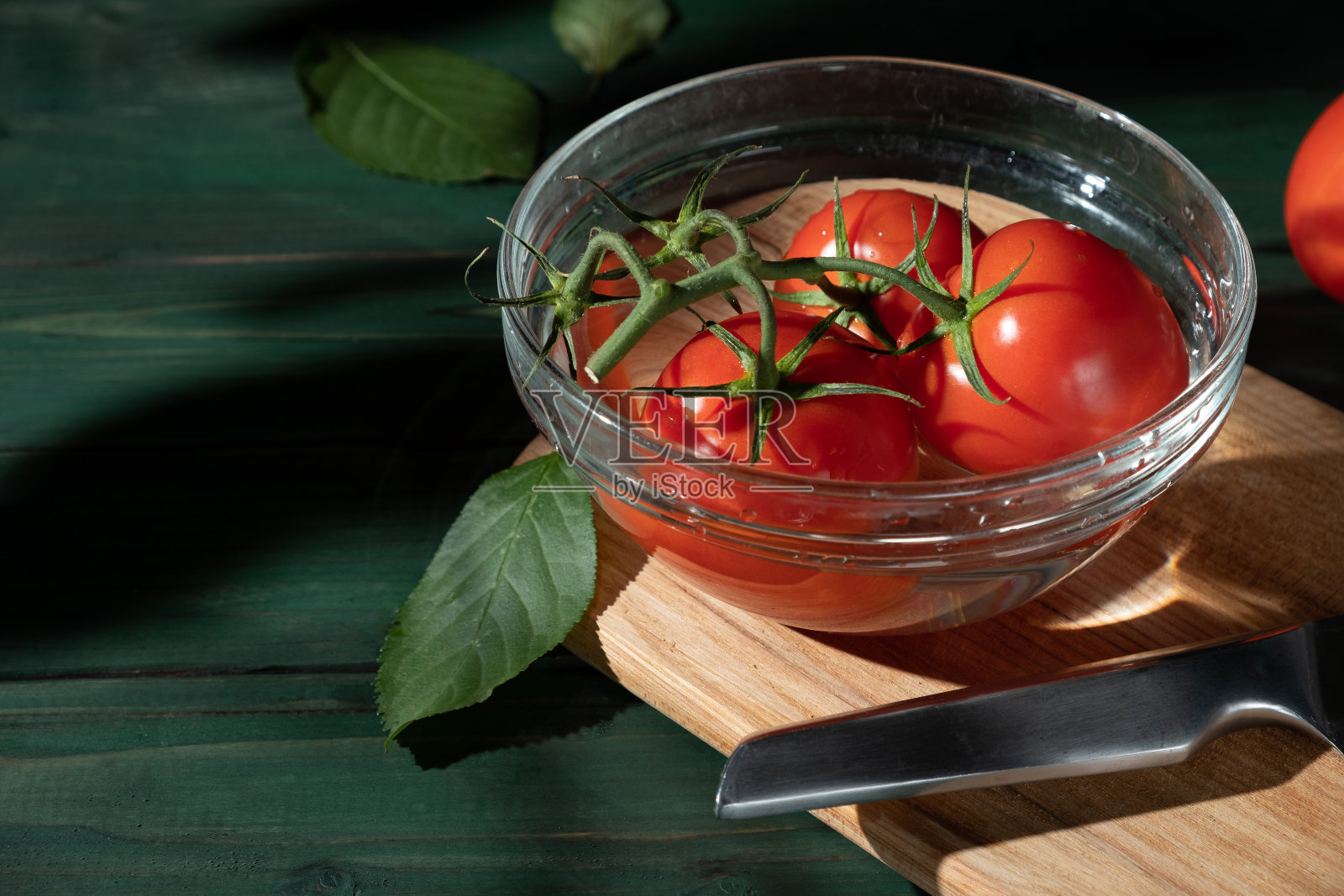 绿色木制背景上碗里的一枝西红柿照片摄影图片