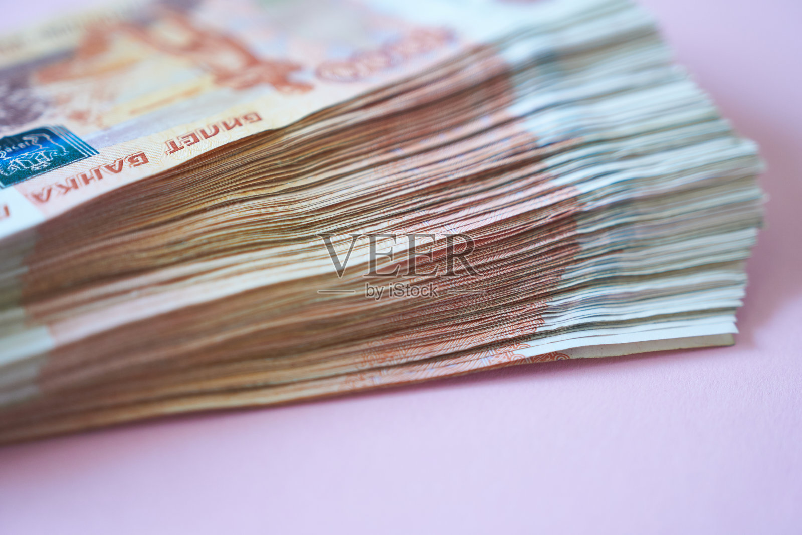 粉红色背景上的一叠5000卢布纸币。照片摄影图片