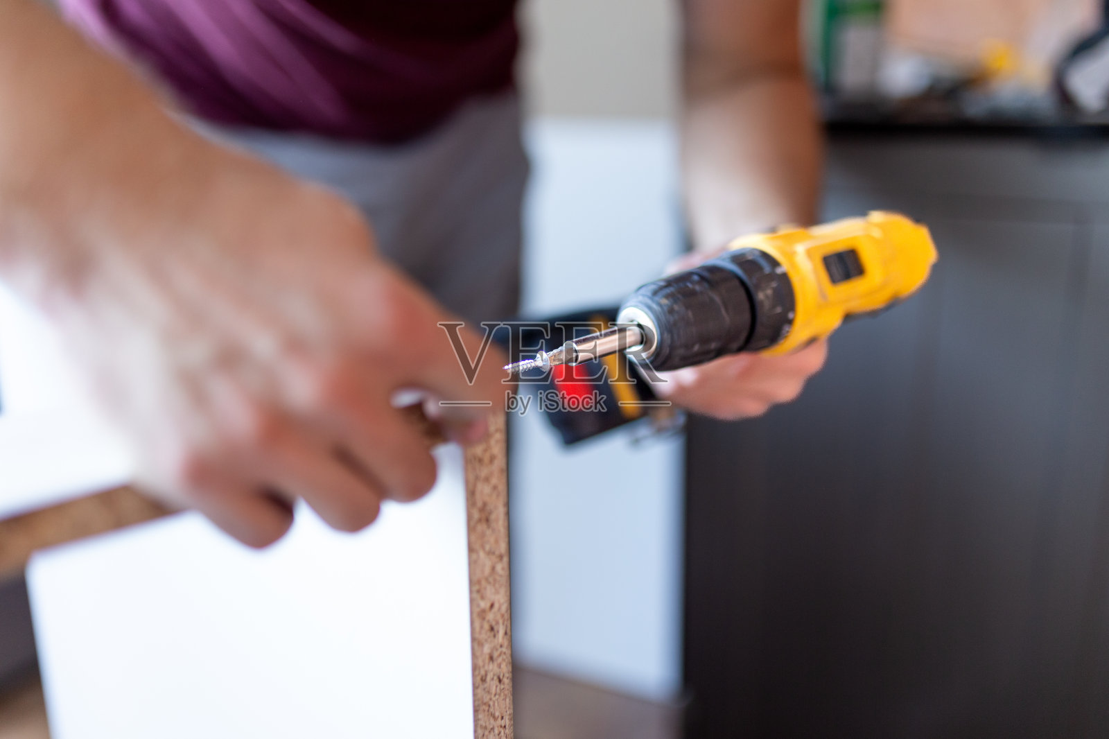 在安装木制厨房货架时,手持电池螺丝刀的男子特写照片摄影图片