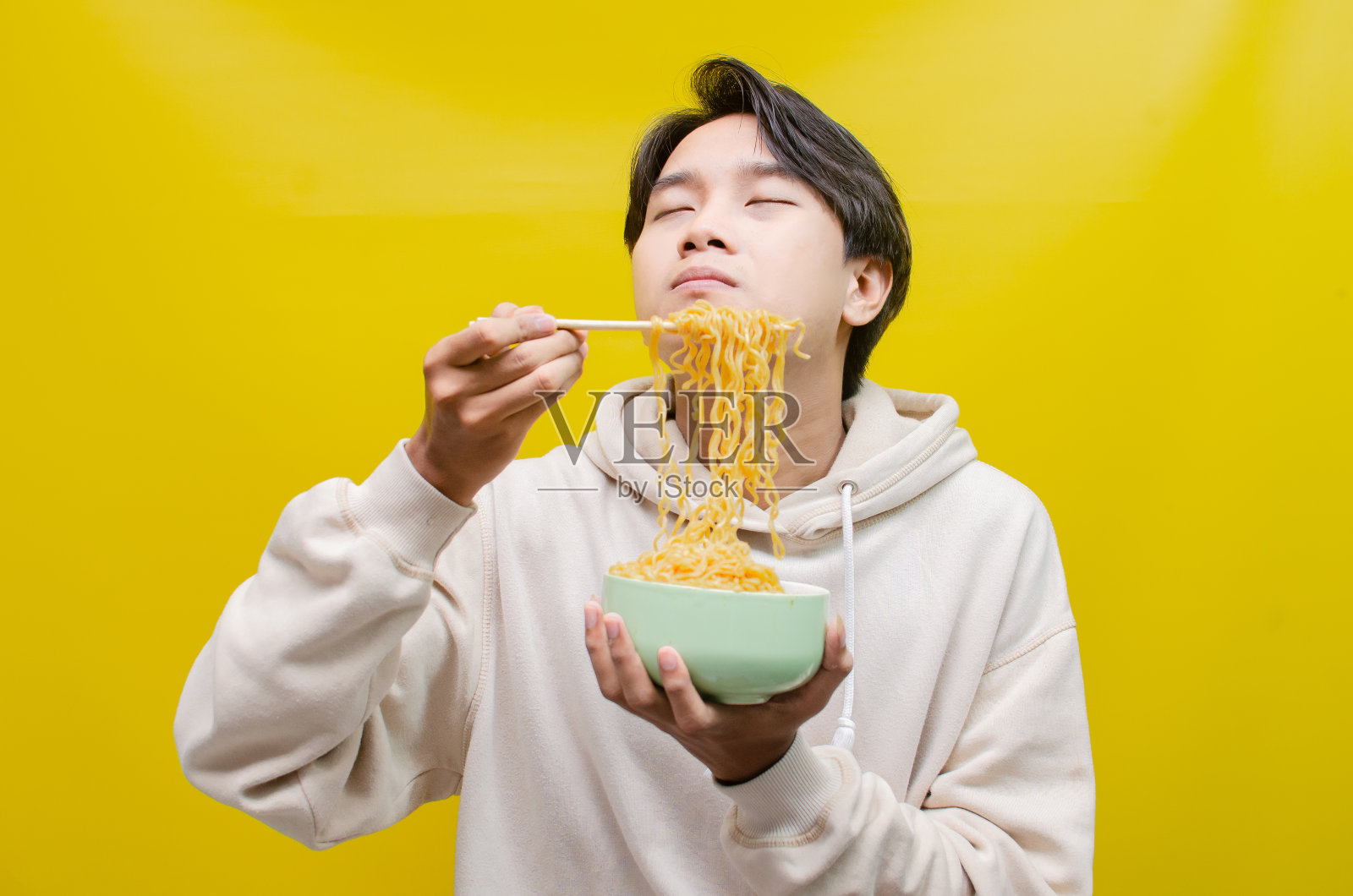 一个男人在吃面条的时候露出美味的表情。照片摄影图片