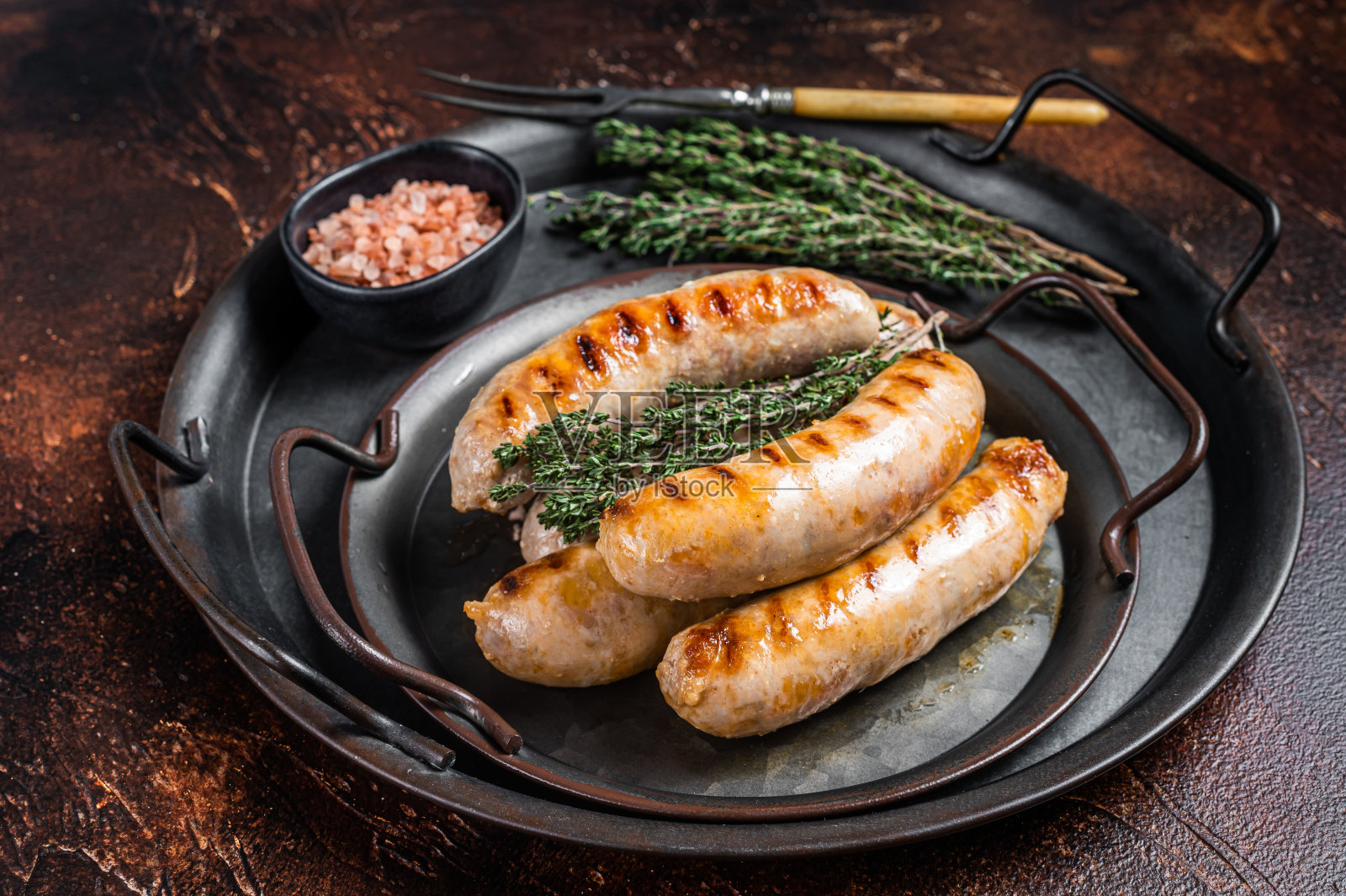 烧烤煎香肠和西班牙辣香肠与香草钢托盘。黑暗的背景。俯视图照片摄影图片