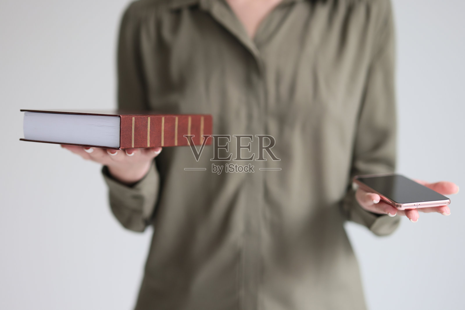 困惑的女人拿着书和智能手机做选择照片摄影图片