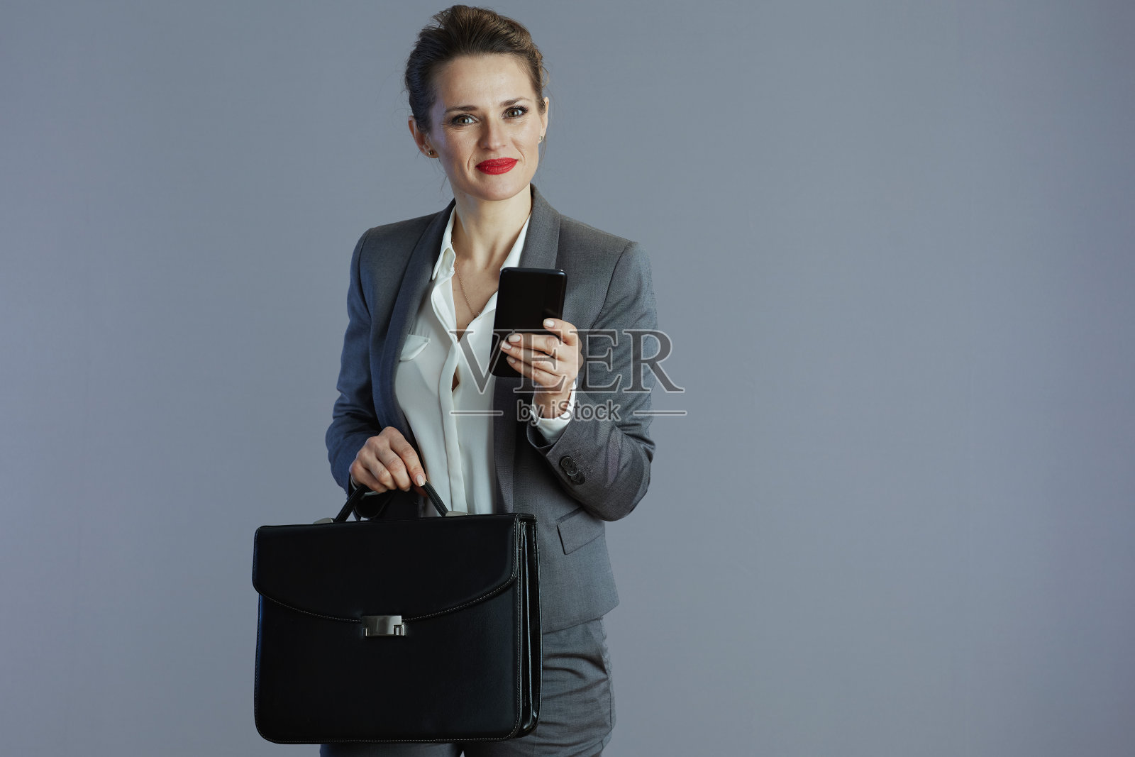 微笑的时髦女工被隔离在灰色背景中照片摄影图片