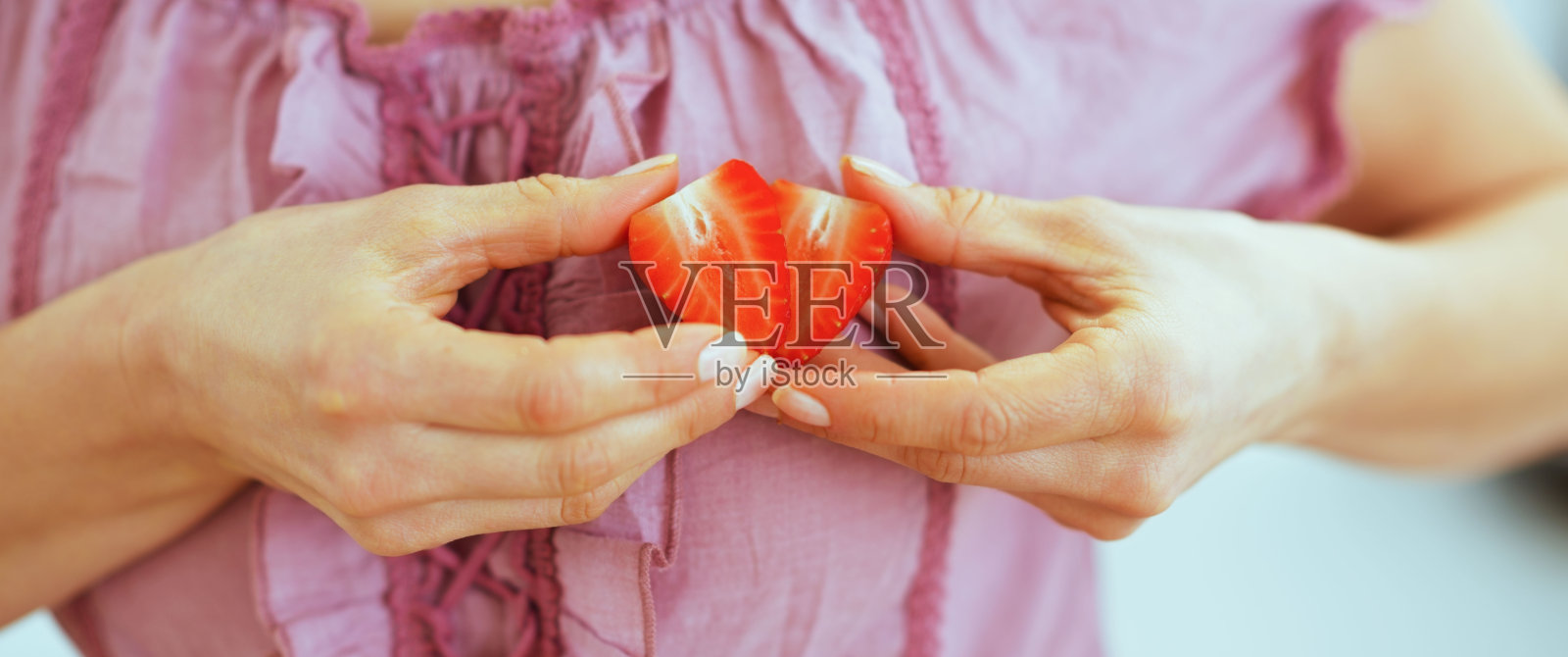 女人用草莓片做心形特写照片摄影图片