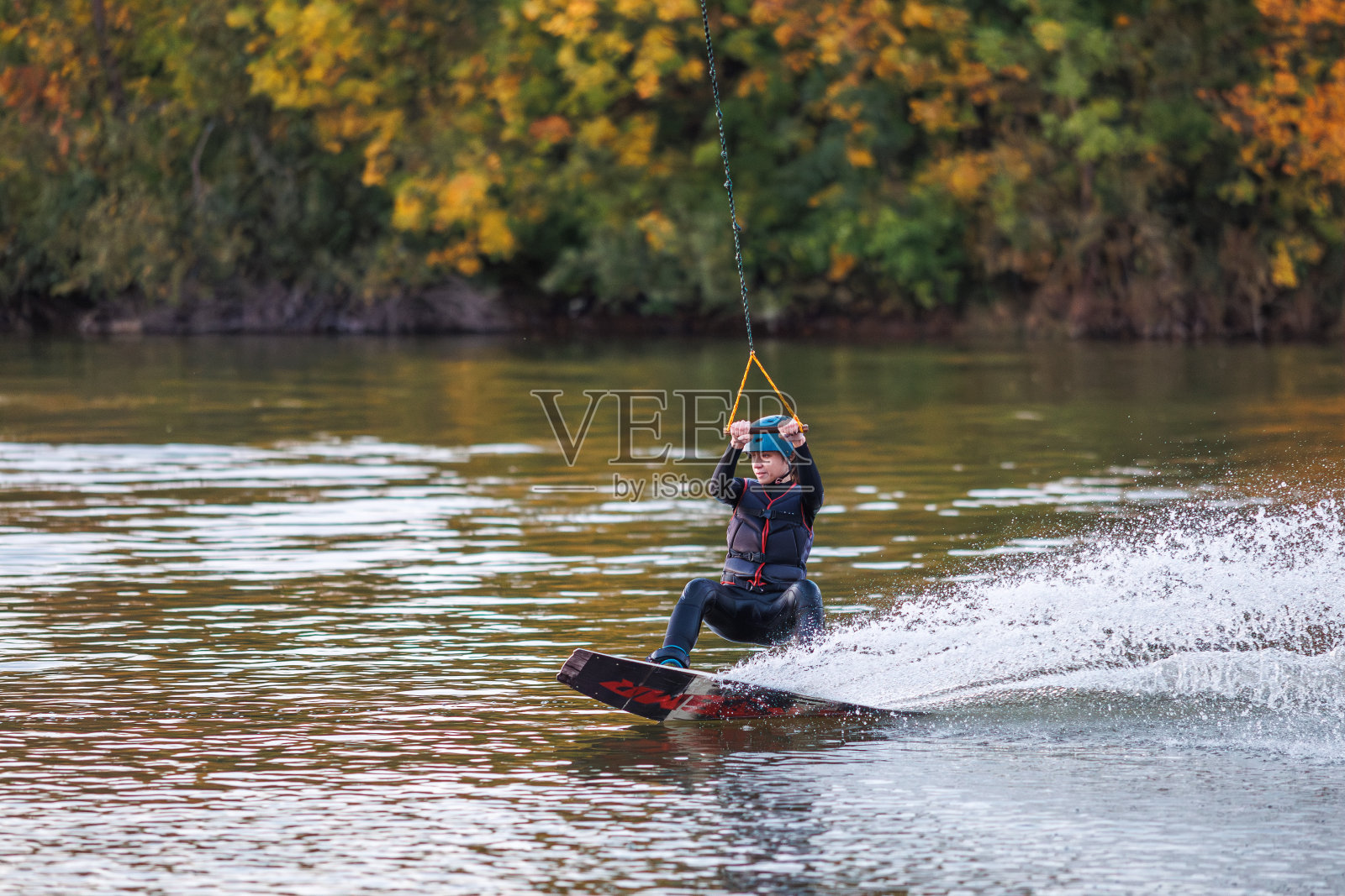滑水板上的女孩。一名运动员在水上表演特技。秋天的公园照片摄影图片