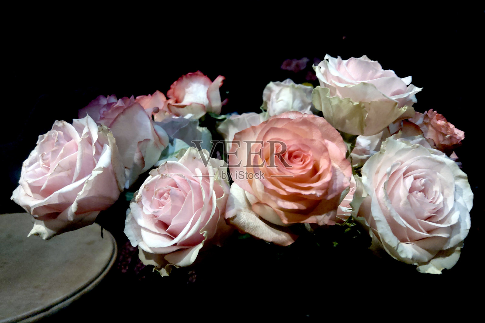 桌上的花瓶里插着一束新鲜的玫瑰。照片摄影图片