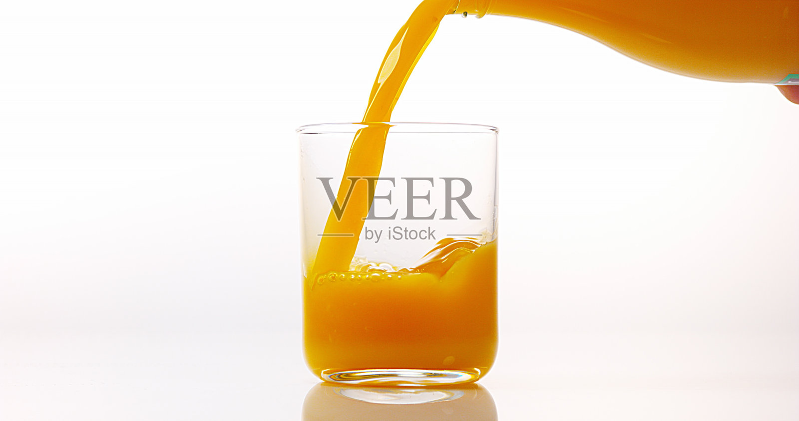 橙汁倒进白色背景的玻璃里照片摄影图片