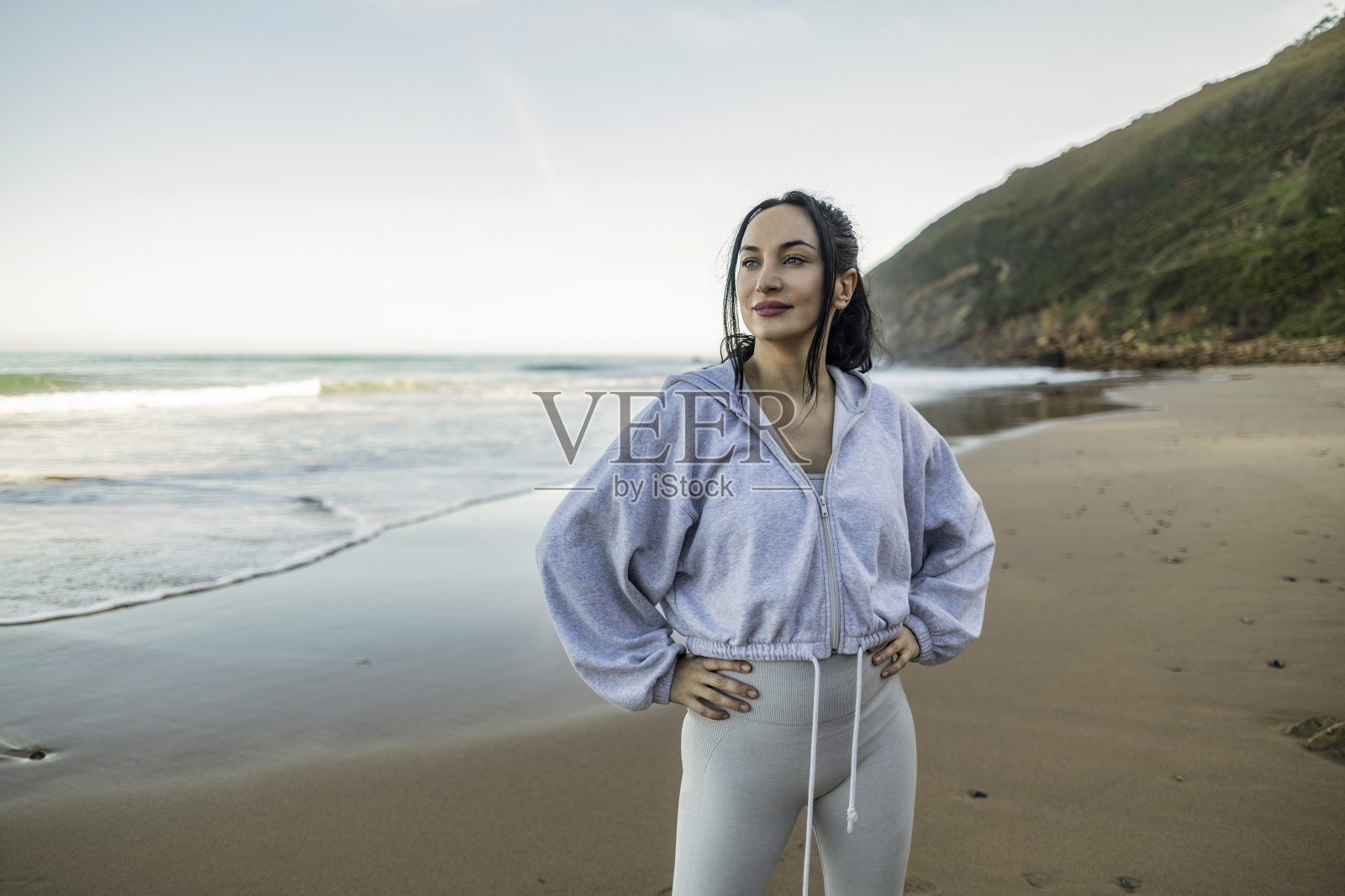 美丽的年轻运动女子躺在沙滩上,看着地平线照片摄影图片