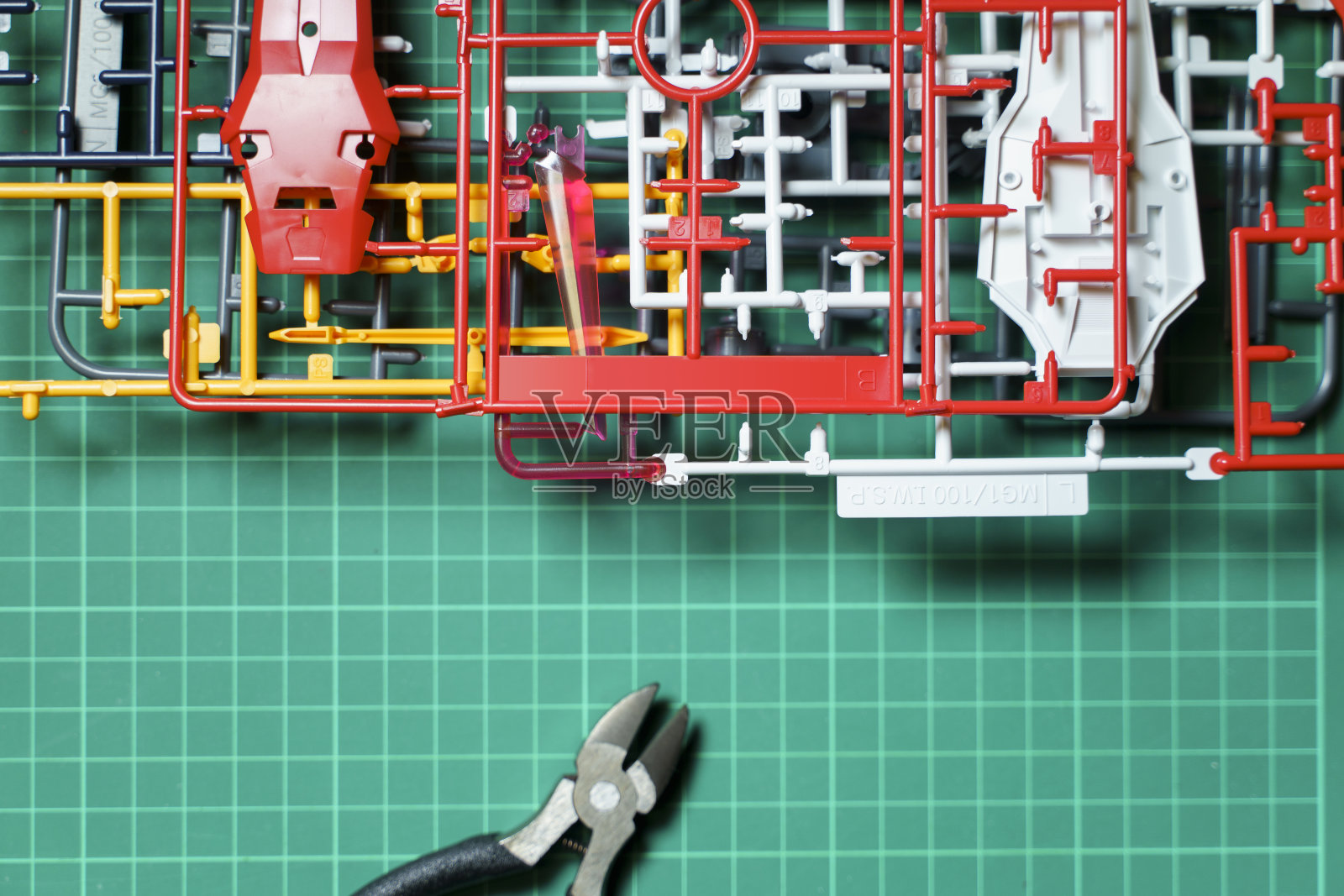 一个锋利的钳子在绿色切割垫与成品塑料模型跑后组装塑料模型玩具。塑料模型通常是用一种叫做注射成型的工艺生产的。照片摄影图片