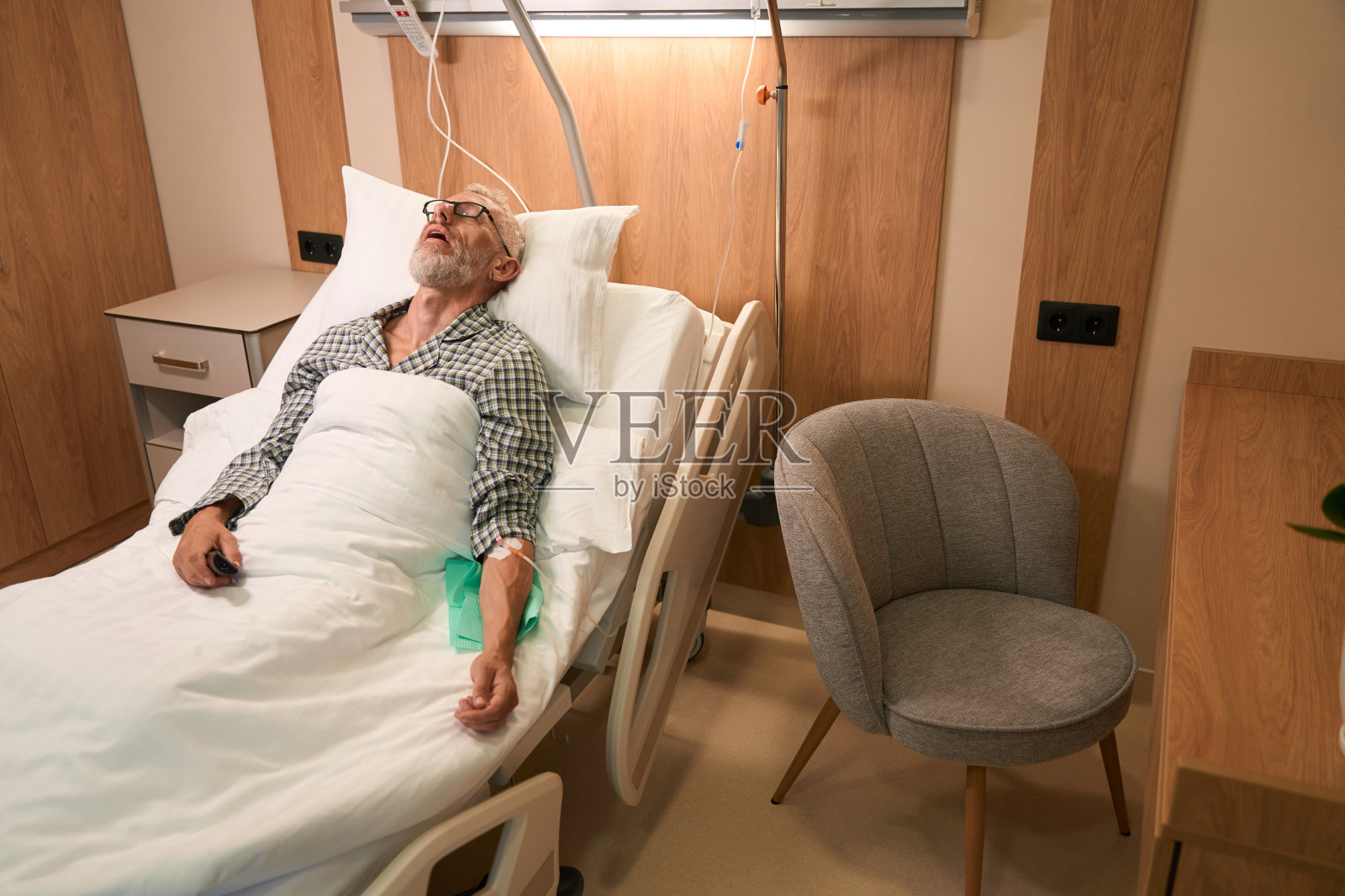 一个白发苍苍的男人躺在一个特殊的移动床上打点滴照片摄影图片