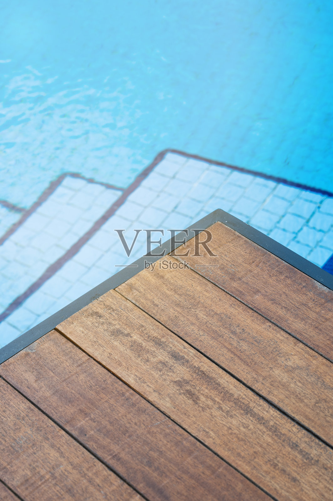 游泳池前的空木桌面,楼梯是蓝色瓷砖。以夏季为背景的产品演示展示概念。照片摄影图片