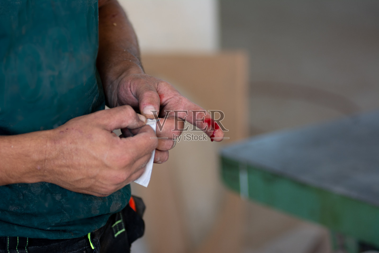 木工店的工人把创可贴贴在受伤的手指上照片摄影图片