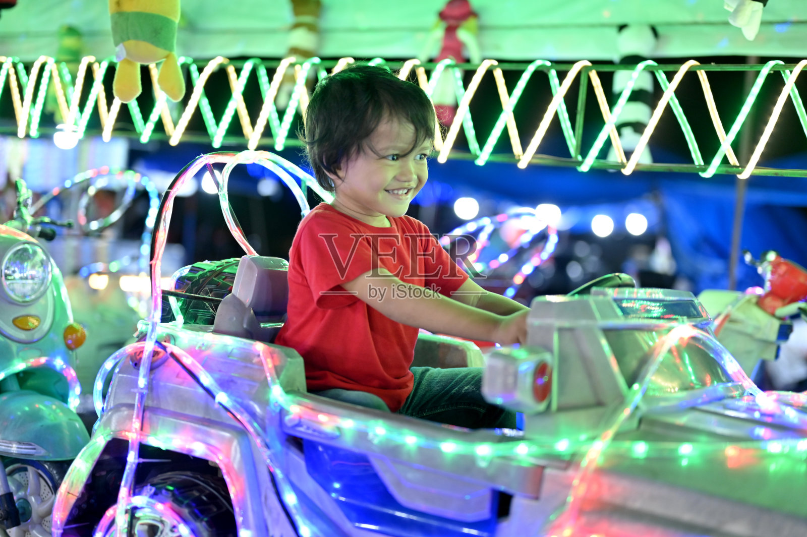 一个亚洲小孩开着玩具车照片摄影图片