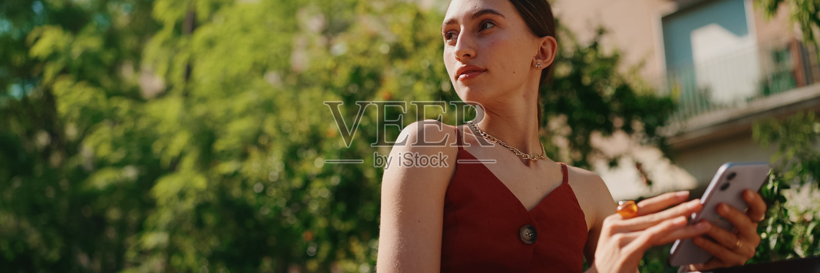 在城市背景下,年轻女子坐在街上的长椅上自拍,视频通话。微笑女孩使用社交媒体,流媒体服务照片摄影图片