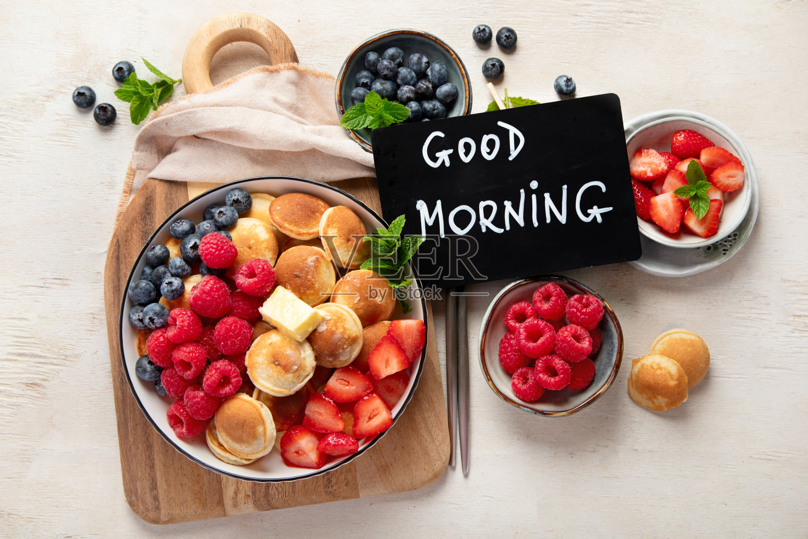 美味的蓝莓,草莓和覆盆子煎饼。甜美可口的早餐在浅色的背景照片摄影图片