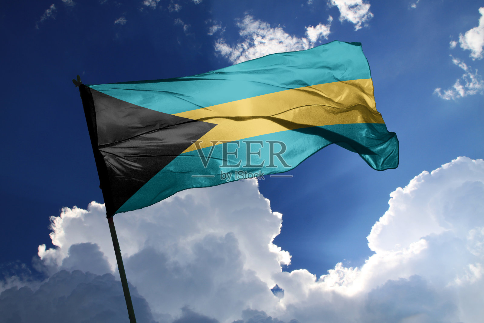 在晴朗的日子里,巴哈马国旗在风中飘扬。照片摄影图片