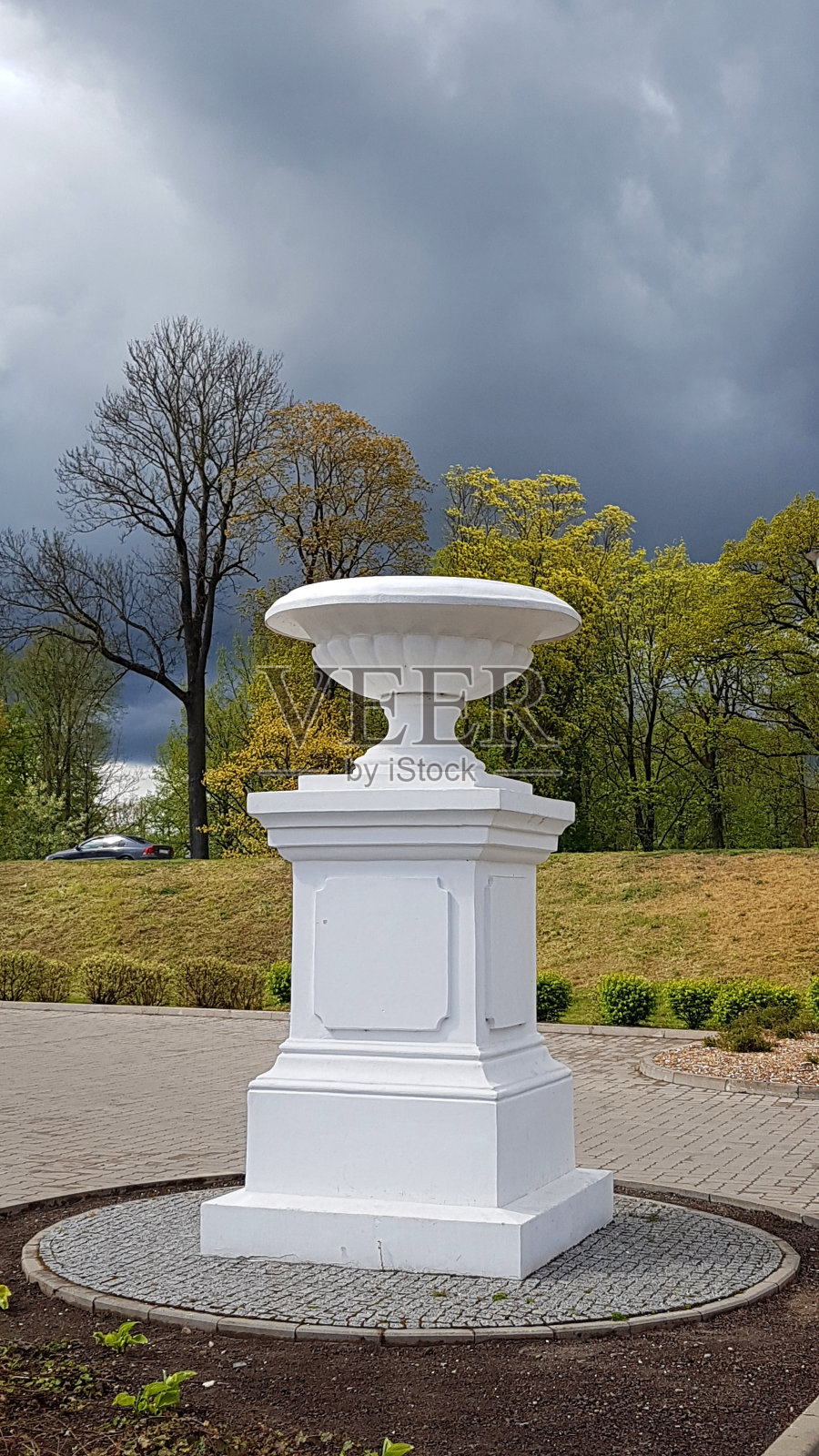 一个阴天,拉脱维亚耶尔加瓦市,历史悠久的白色石碗放在鲜花基座上照片摄影图片