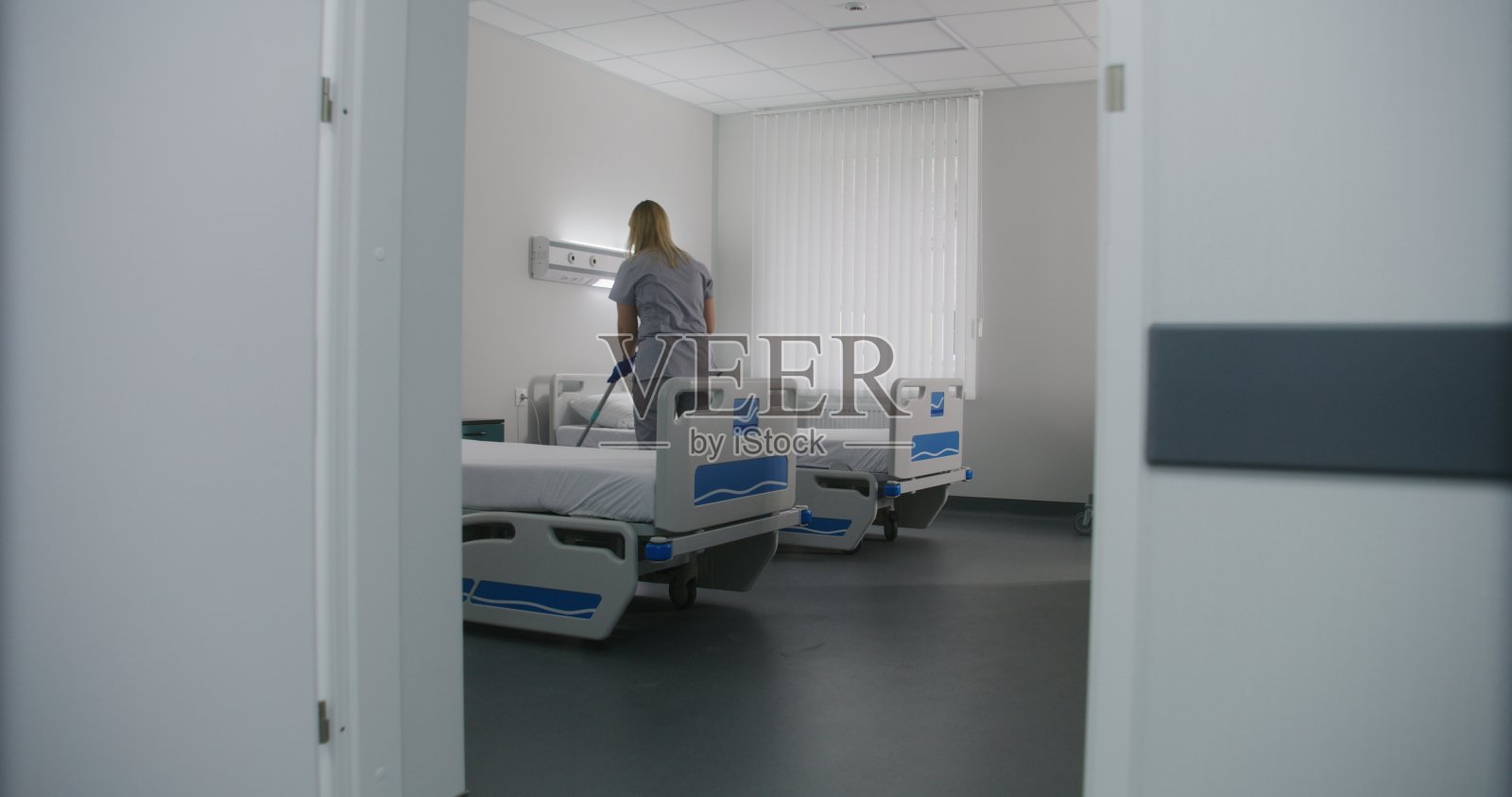 成年护士在医院病房的病床间拖地照片摄影图片