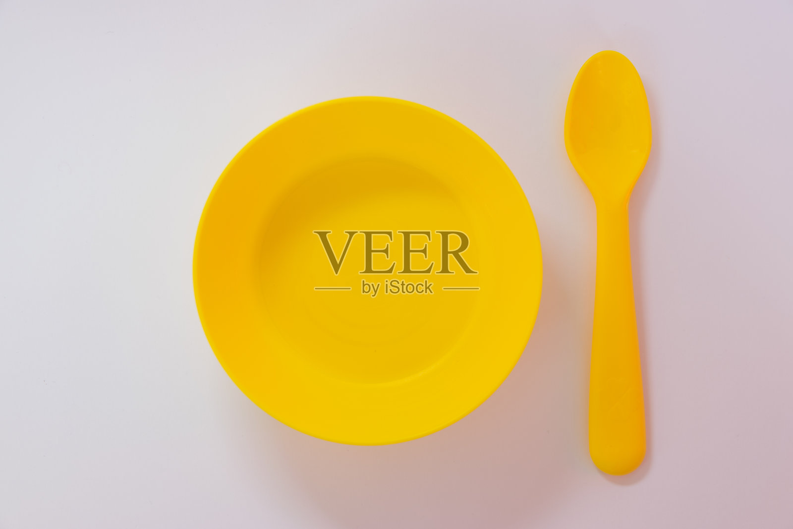 白色背景上的黄色勺子和盘子。照片摄影图片