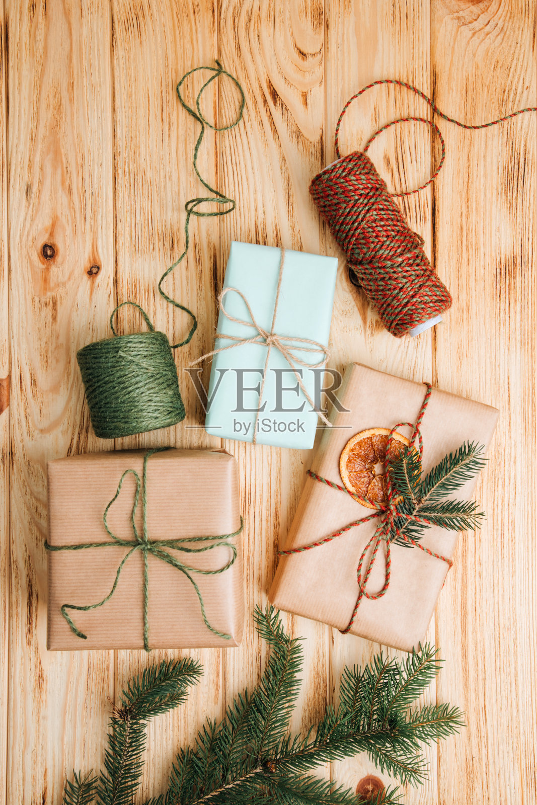 问候的背景。礼品包装在棕色的纸与干橙和针叶树的树枝在一个轻的木制背景照片摄影图片