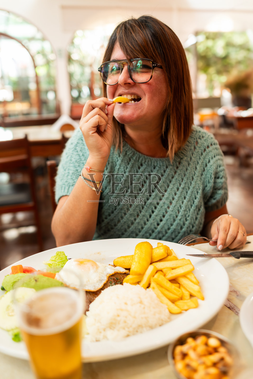 有趣的女人咬着薯条从她的牛排到可怜的盘子。传统的秘鲁食物。照片摄影图片