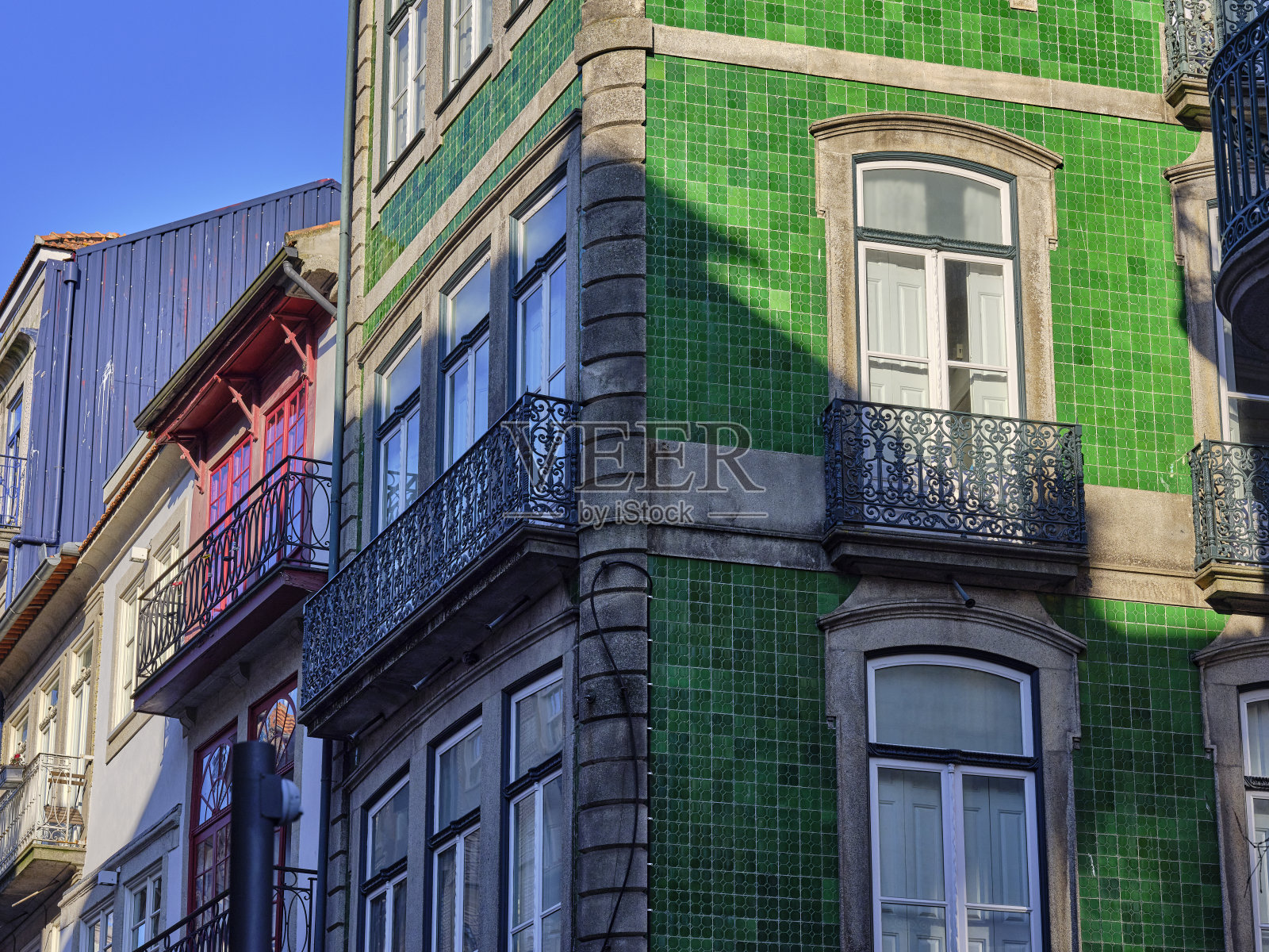 典型的葡萄牙房屋,覆盖着五颜六色的azulejos,在葡萄牙波尔图市的历史地段。房屋立面,窗户,阳台,栏杆,彩色陶瓷的细节。照片摄影图片