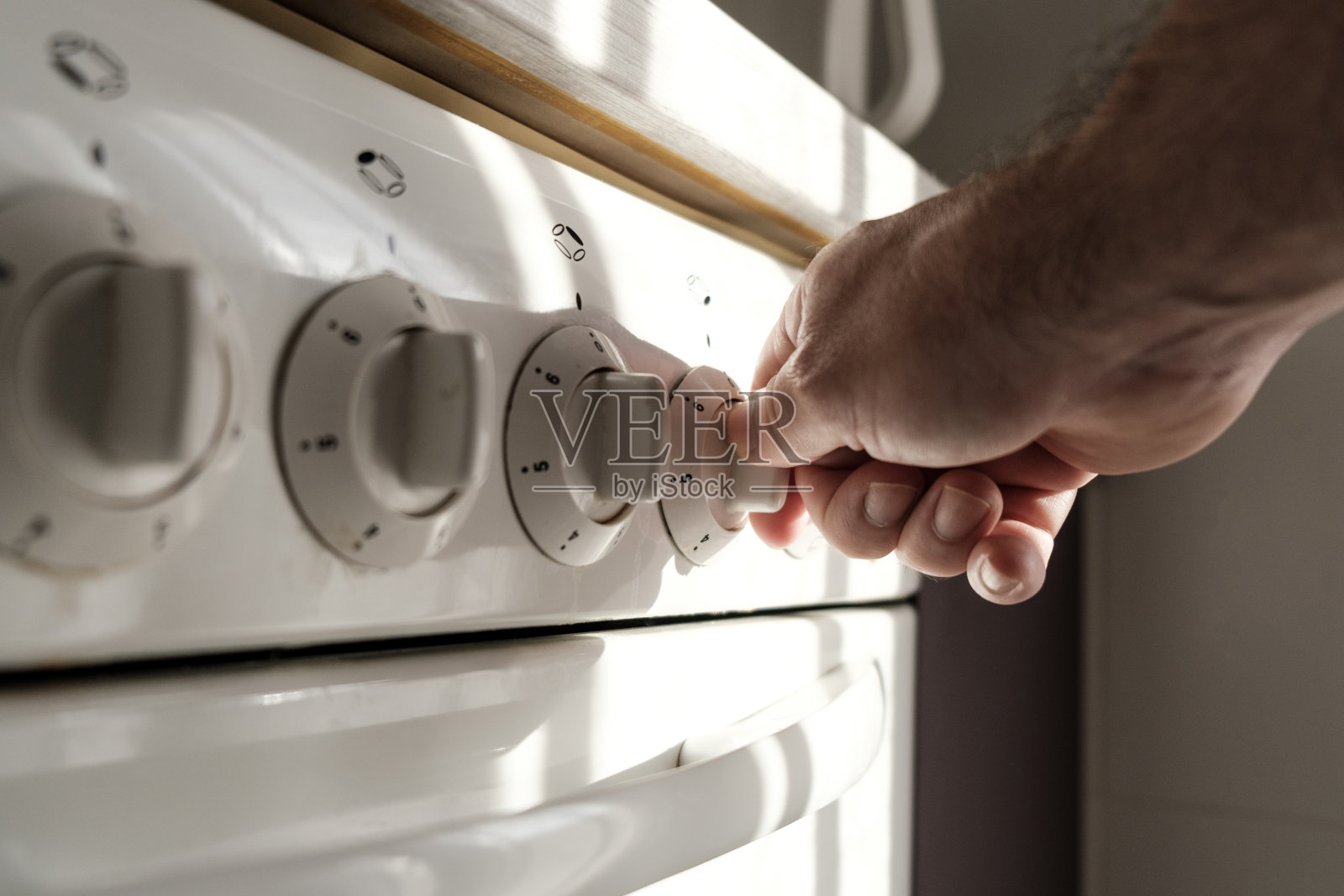 男性手使用炊具旋钮。照片摄影图片