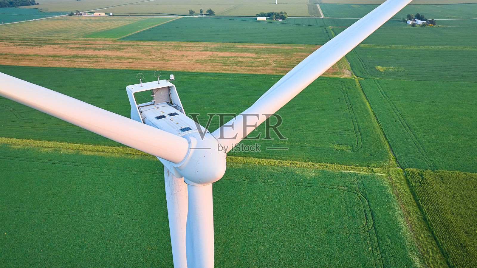 郁郁葱葱的绿色田野中风力涡轮机叶片上的日出黄金时段照明航拍特写照片摄影图片