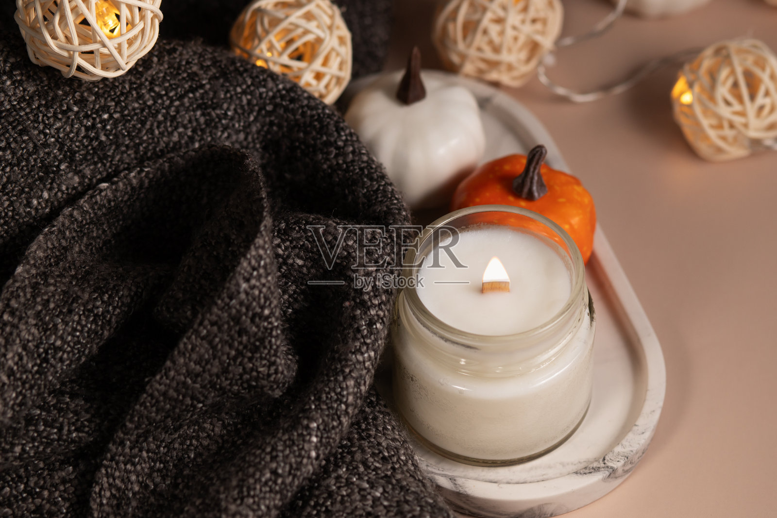 燃烧的蜡烛和舒适的毯子,秋天的南瓜装饰,芬芳的室内,放松的水疗氛围照片摄影图片