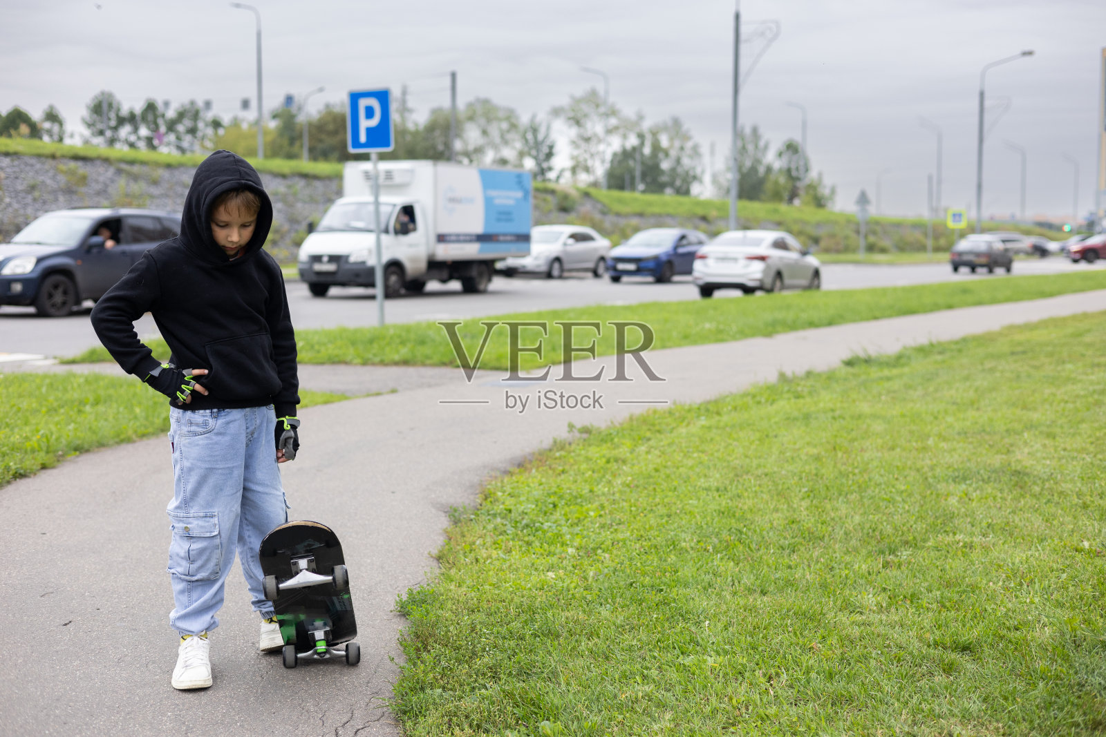 副本的空间。一个在城市街道上玩滑板的小男孩。一个孩子在人行道上学滑板。一个时髦的男孩在城市里踩着滑板散步。的生活方式。照片摄影图片