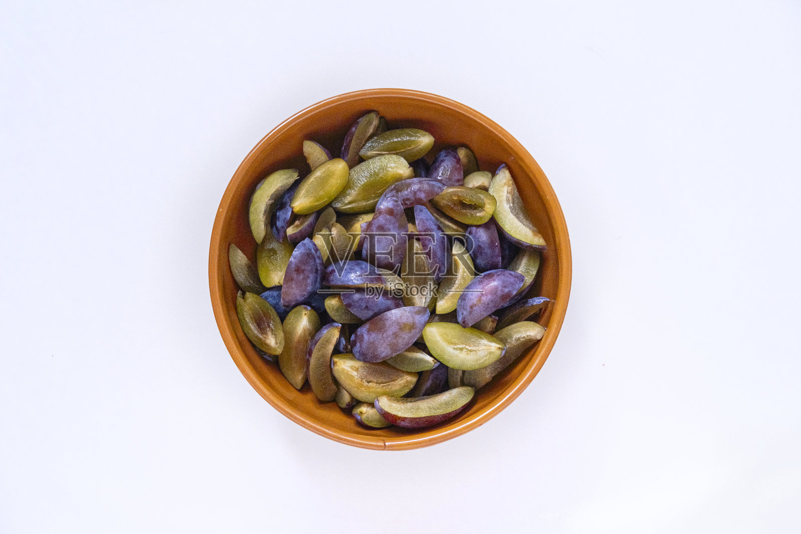 白底碗里的李子片。照片摄影图片