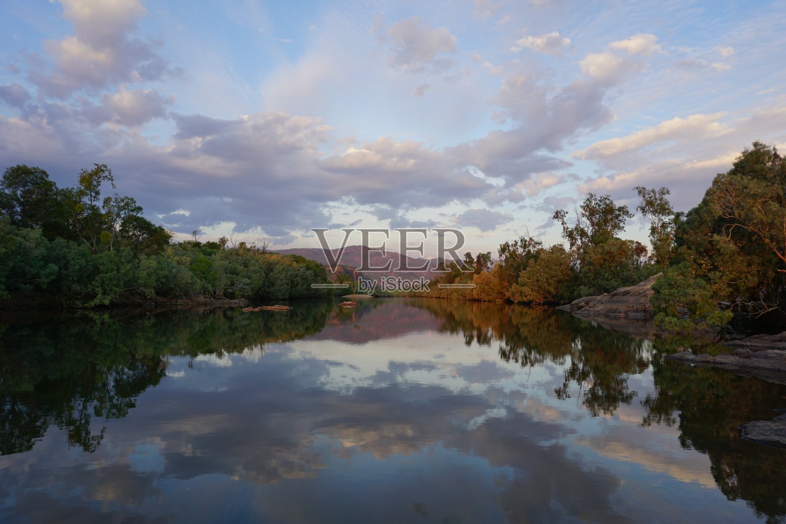 在澳大利亚昆士兰州内陆小镇奇拉戈的一条河上,粉红色的日落展现了水中山脉和树木的倒影照片摄影图片