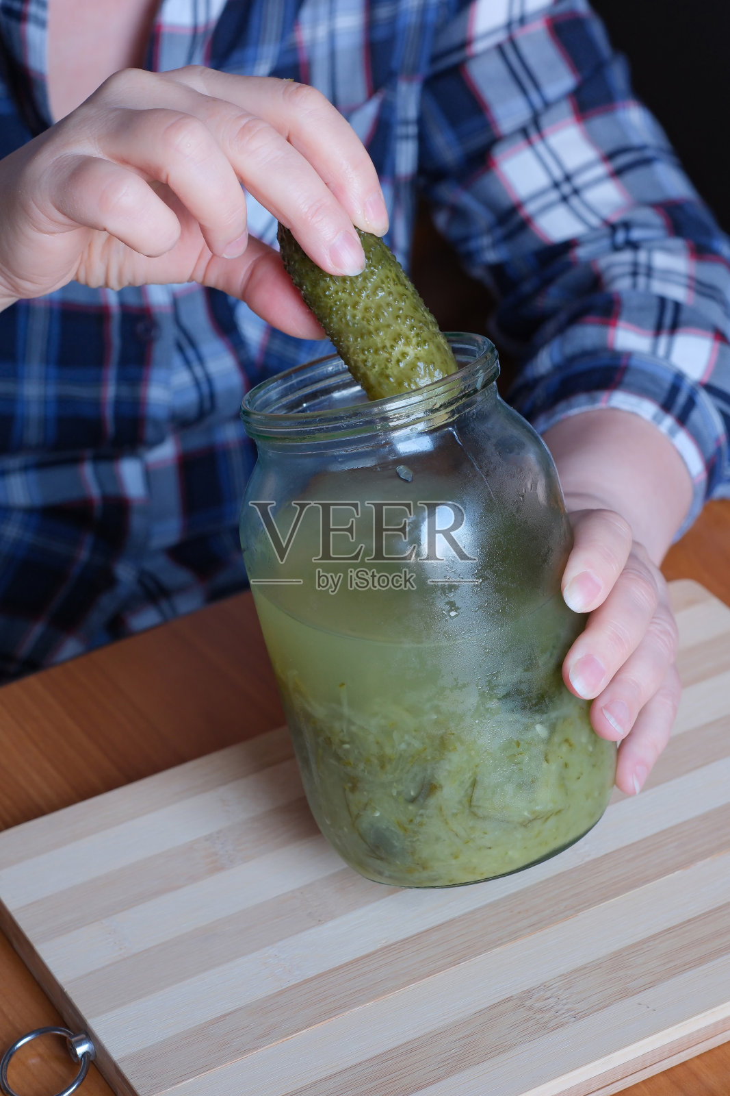 一位老妇人的手拿出美味的自制腌黄瓜照片摄影图片