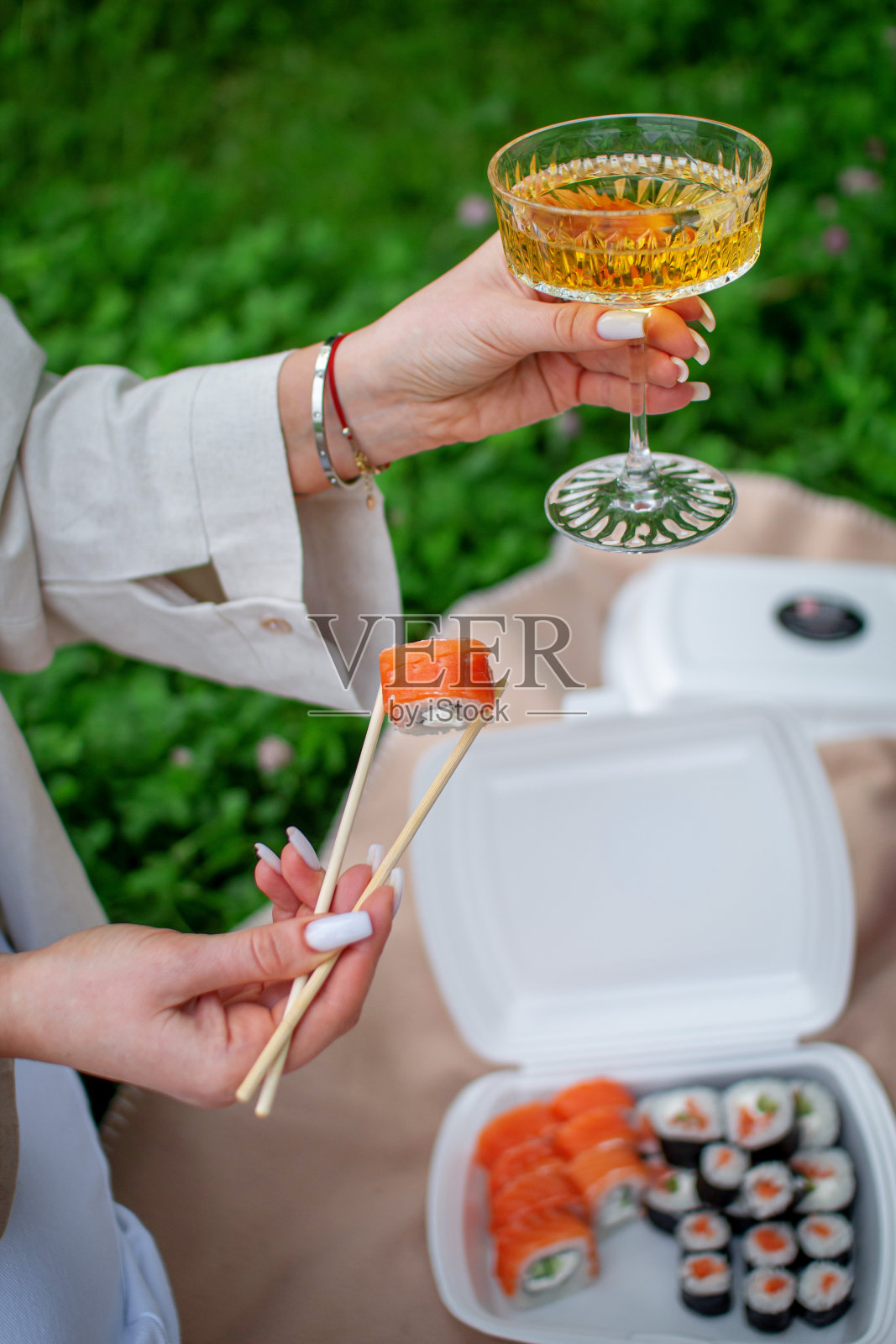 一个女孩拿着杯子里的饮料和寿司卷,在加州的夏日公园里野餐照片摄影图片