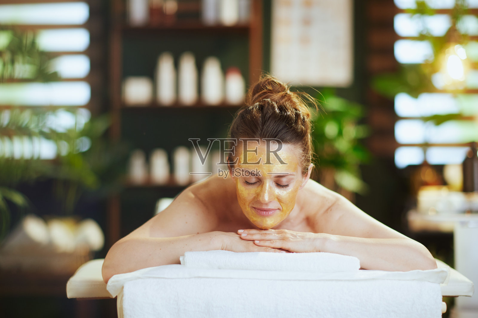 放松的40岁妇女在水疗沙龙躺在按摩床上照片摄影图片