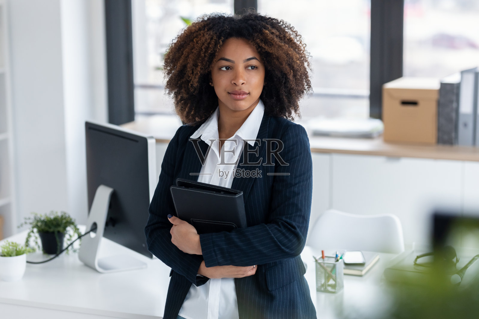 优雅美丽的商务女性在现代办公室里拿着数码平板电脑向前看照片摄影图片