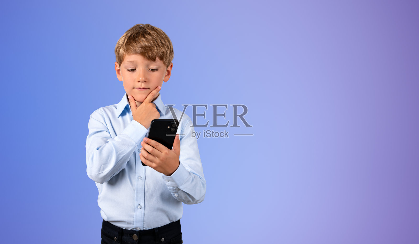 孩子用智能手机,手放在下巴上,复制空间渐变背景照片摄影图片