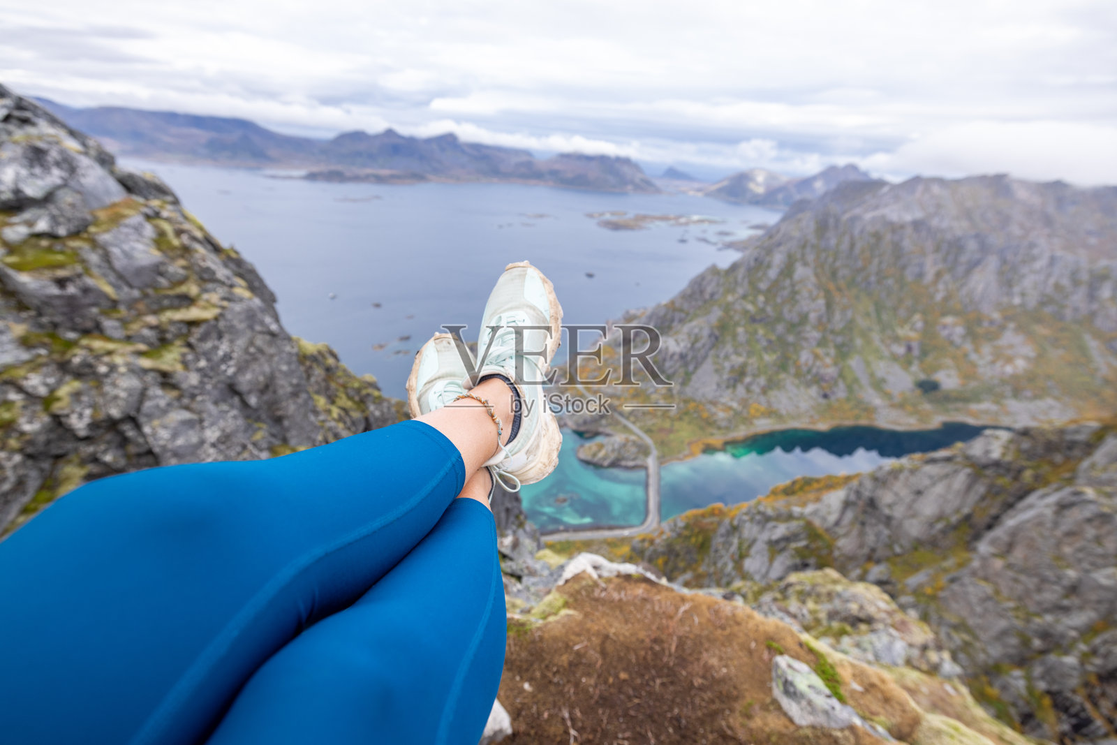 女徒步者在岩石上休息,凝视着秋天的景色照片摄影图片