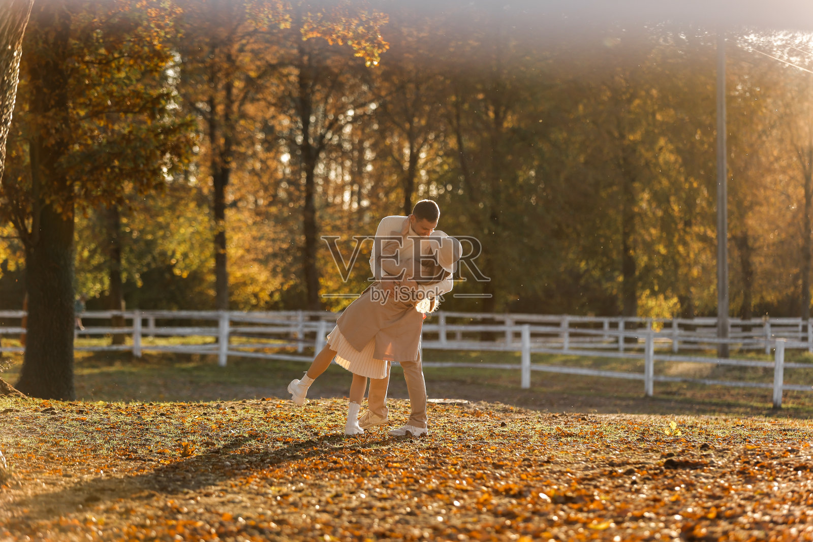 年轻时髦的情侣在秋天的公园里拥抱亲吻。可爱的浪漫时刻之间的男人和女人在爱,看着对方。幸福的家庭。爱情,青春,幸福的概念。照片摄影图片