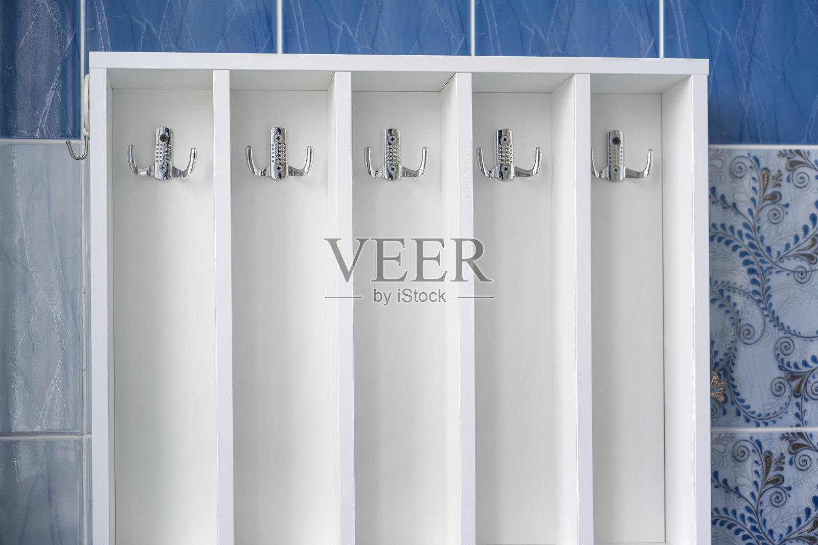 金属衣架钉在白色的木制开放式橱柜里,用来放毛巾和衣服照片摄影图片