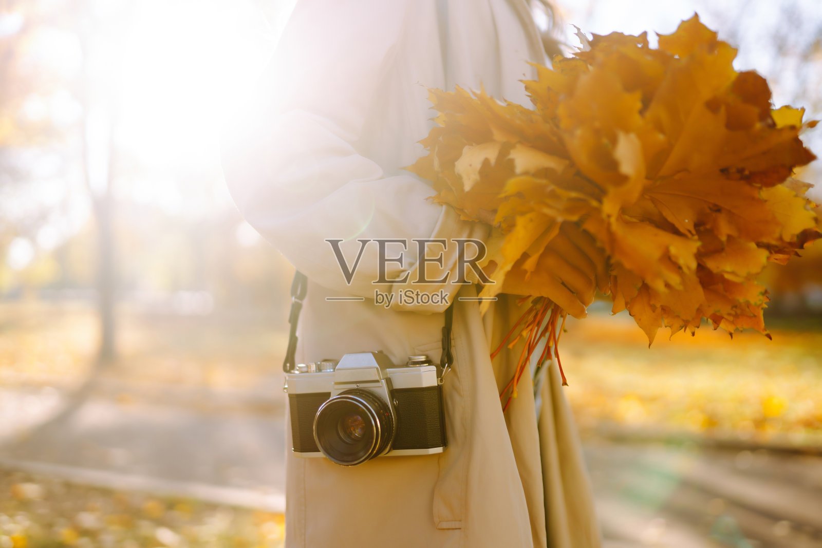 快乐的年轻女子穿着时髦的衣服,用复古相机拍照。照片摄影图片